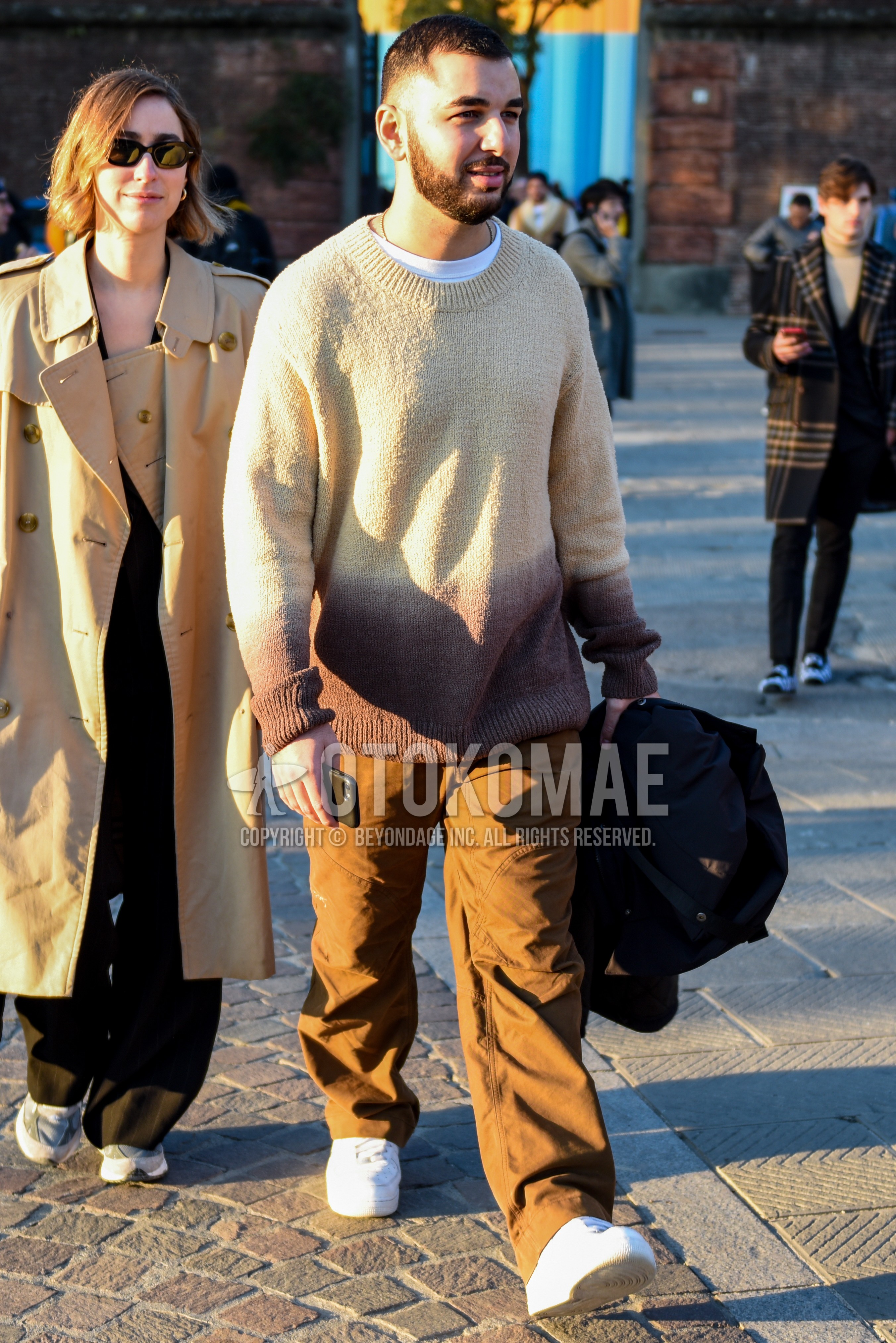 Men's spring autumn outfit with beige plain sweater, white plain t-shirt, beige plain chinos, white low-cut sneakers.
