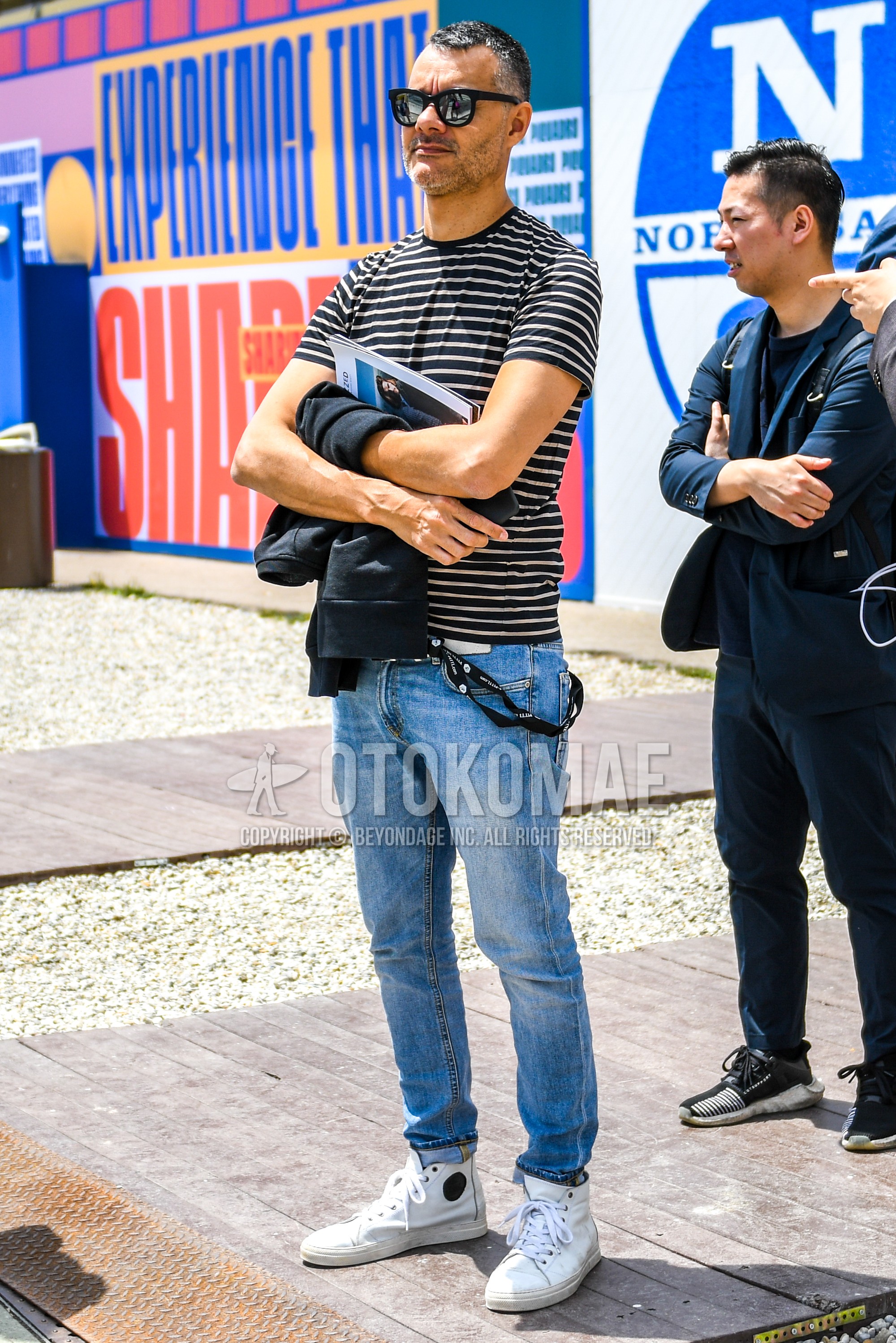 Men's summer outfit with plain sunglasses, black white horizontal stripes t-shirt, blue plain denim/jeans, white high-cut sneakers.