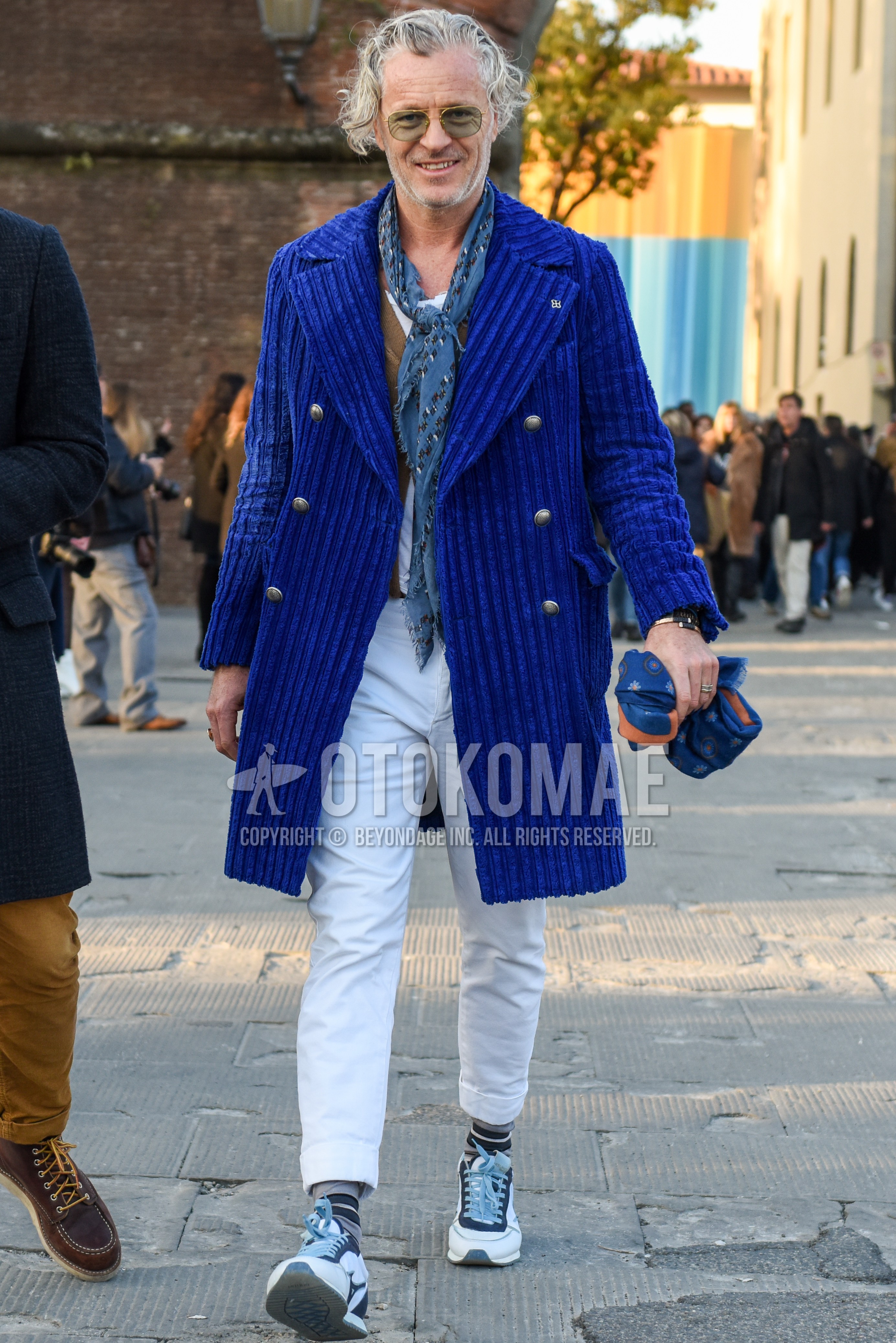 Men's autumn winter outfit with gold plain sunglasses, gray scarf scarf, blue plain ulster coat, beige plain cardigan, white plain t-shirt, white plain cotton pants, white plain cropped pants, white navy low-cut sneakers.