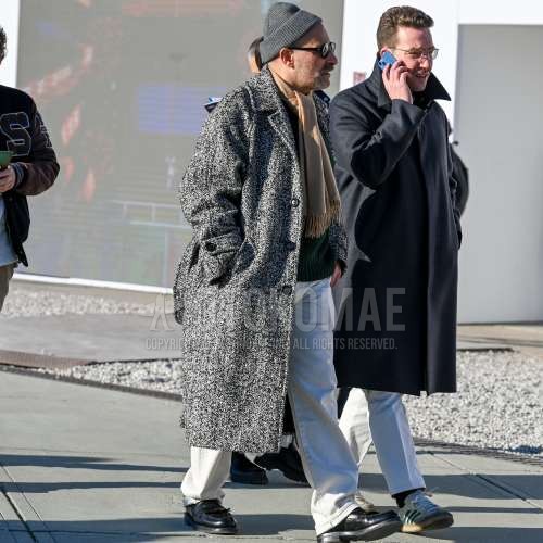 グレー無地のニットキャップ、黒無地のサングラス、ベージュ無地のマフラー/ストール、グレー無地のアルスターコート、グリーン無地のセーター、白無地のデニム/ジーンズ、黒タッセルローファーの革靴を合わせた冬のメンズコーデ・着こなし。