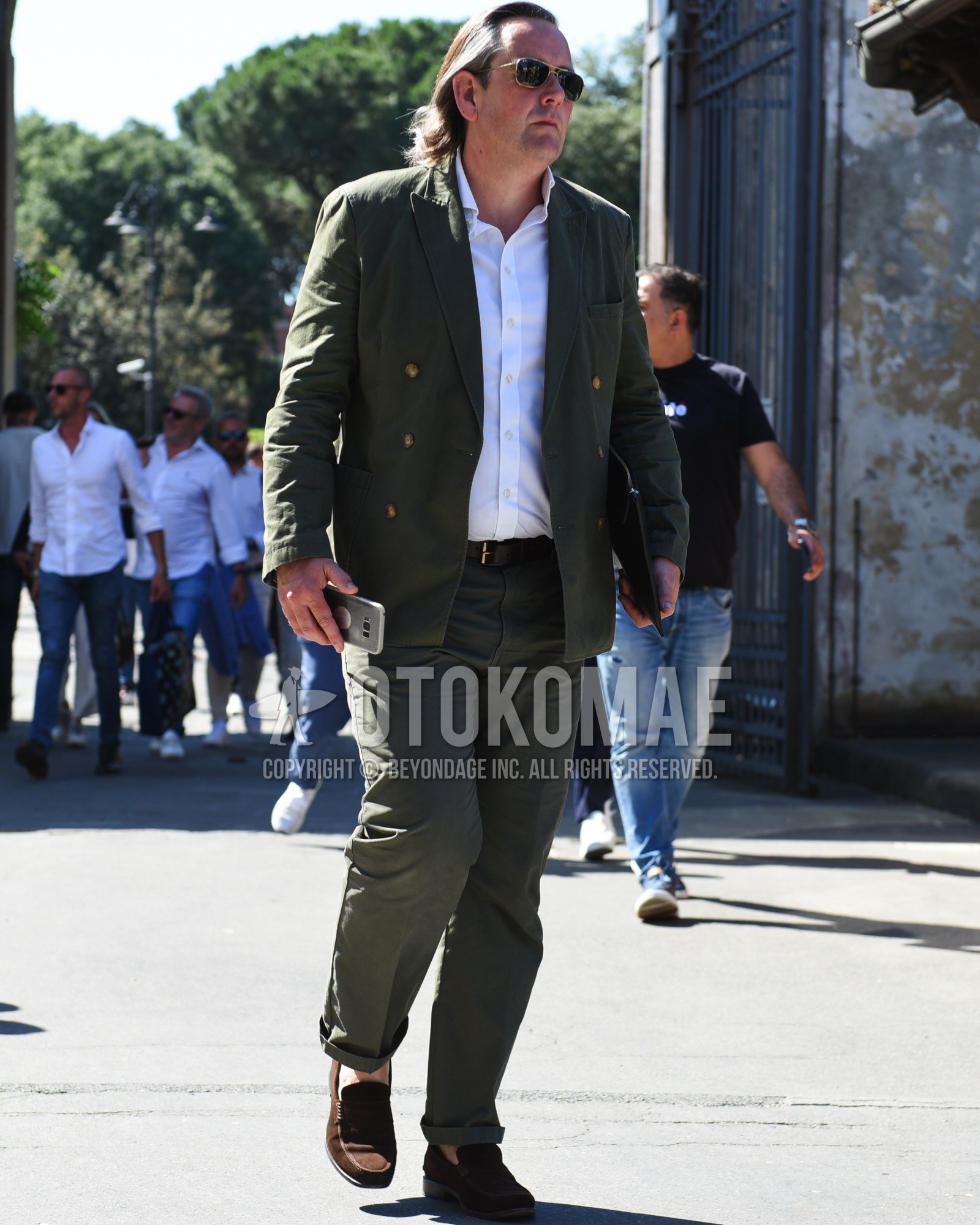 Men's spring summer outfit with gold plain sunglasses, white plain shirt, brown plain leather belt, brown coin loafers leather shoes, brown suede shoes leather shoes, olive green plain suit.