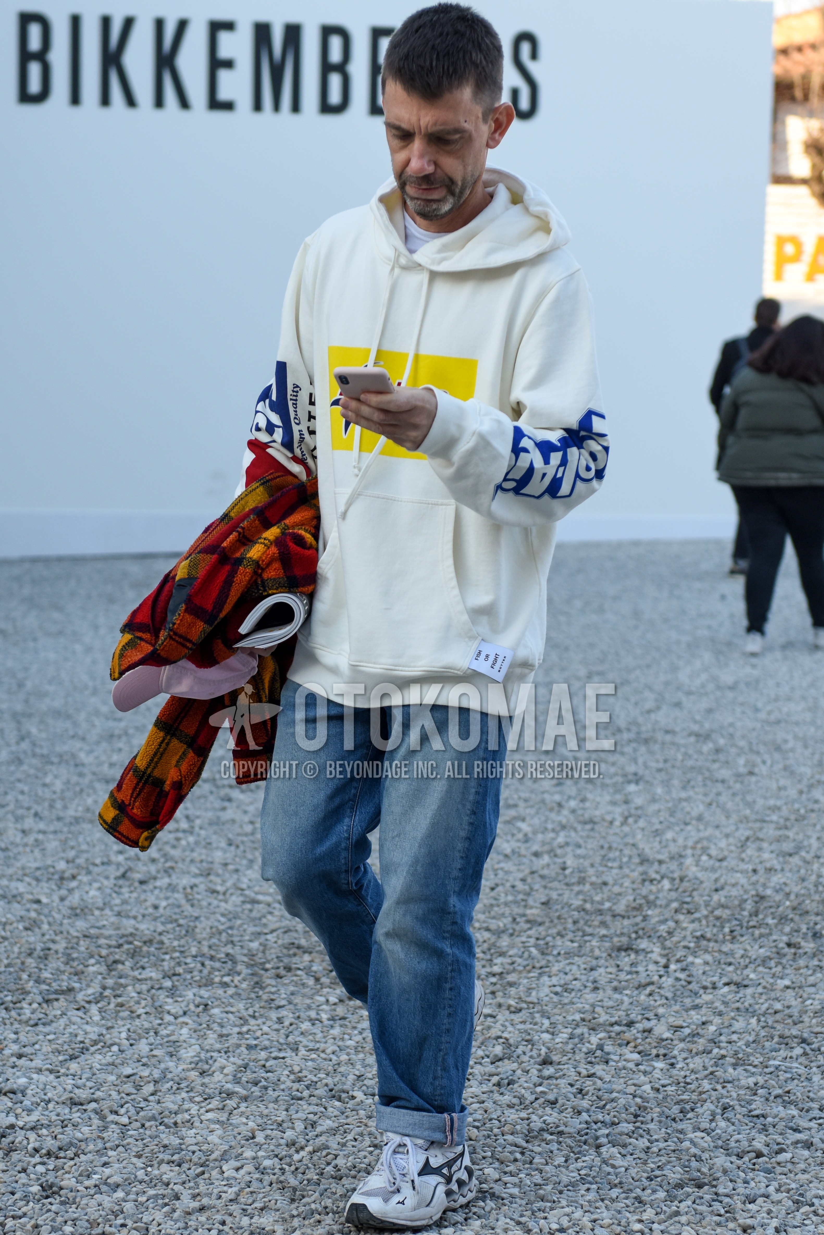 Men's spring autumn outfit with white graphic hoodie, blue plain denim/jeans, white low-cut sneakers.