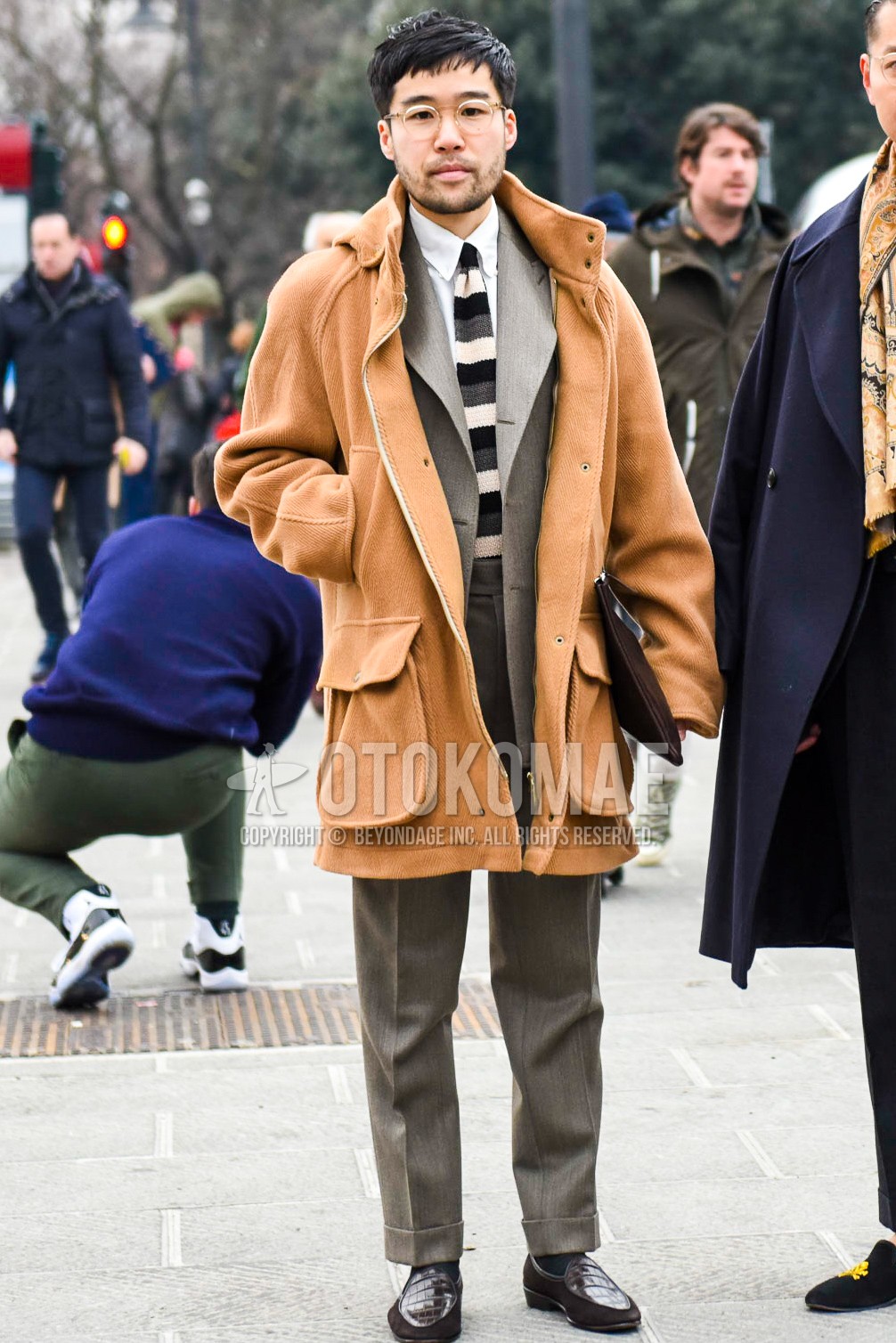 Men's autumn winter outfit with plain glasses, beige plain hooded coat, white plain shirt, black plain socks, brown  loafers leather shoes, gray plain suit, gray black white horizontal stripes knit tie.
