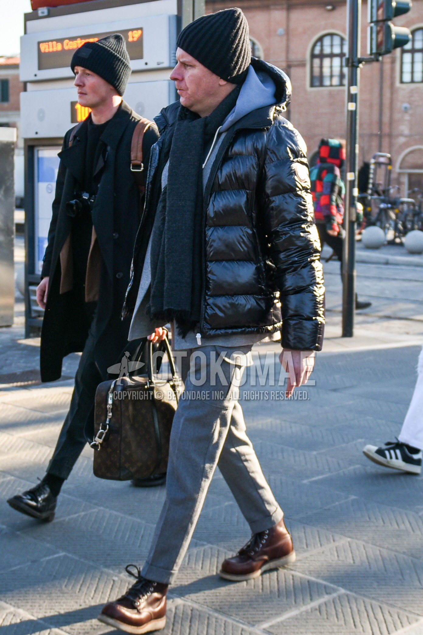 Men's winter outfit with black plain knit cap, dark gray plain scarf, black plain down jacket, gray plain hoodie, gray plain cargo pants, gray plain slacks, brown work boots, brown bag briefcase/handbag.