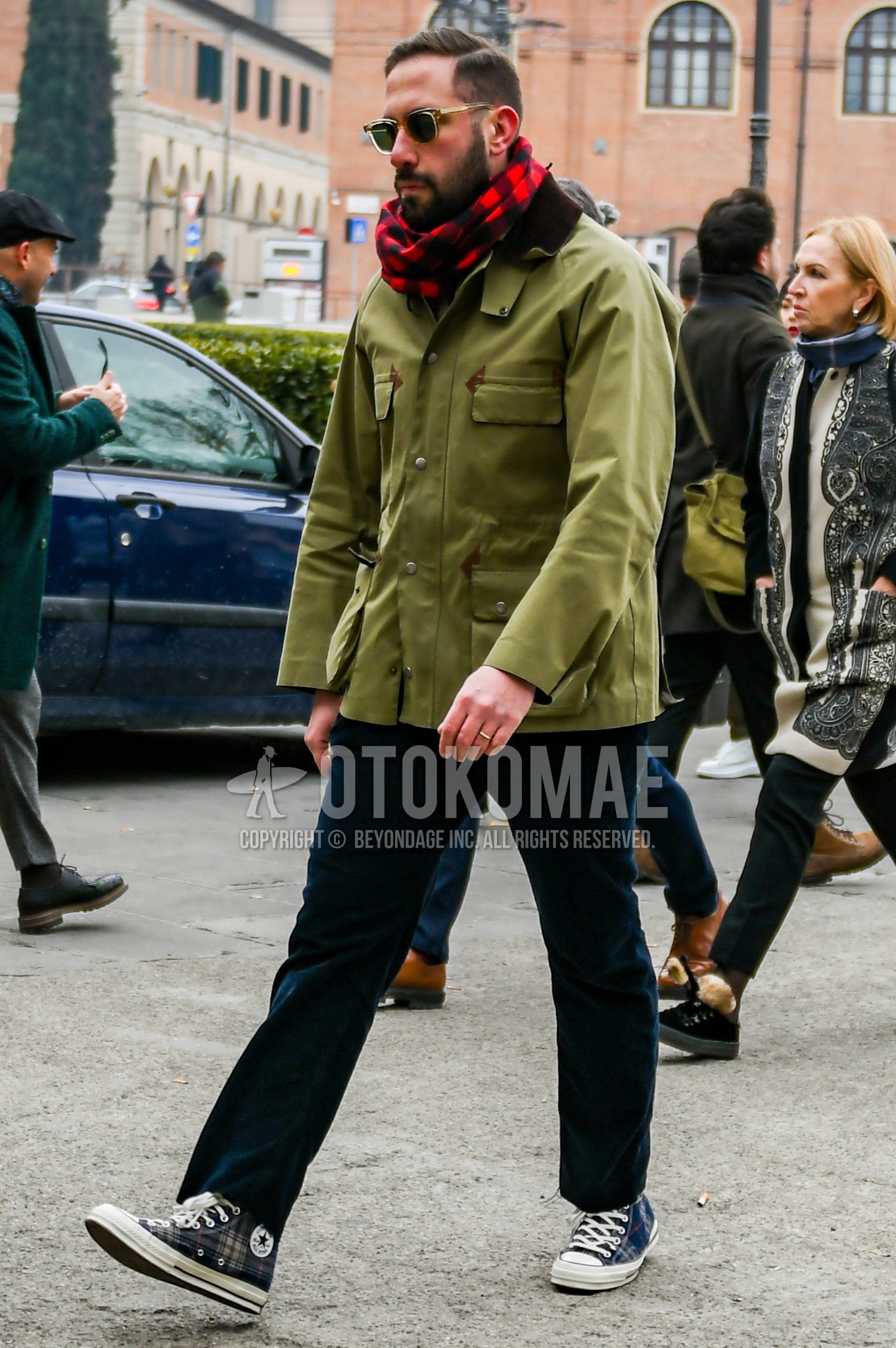 Men's autumn winter outfit with clear plain sunglasses, red black check scarf, olive green plain field jacket/hunting jacket, navy plain winter pants (corduroy,velour), navy high-cut sneakers.