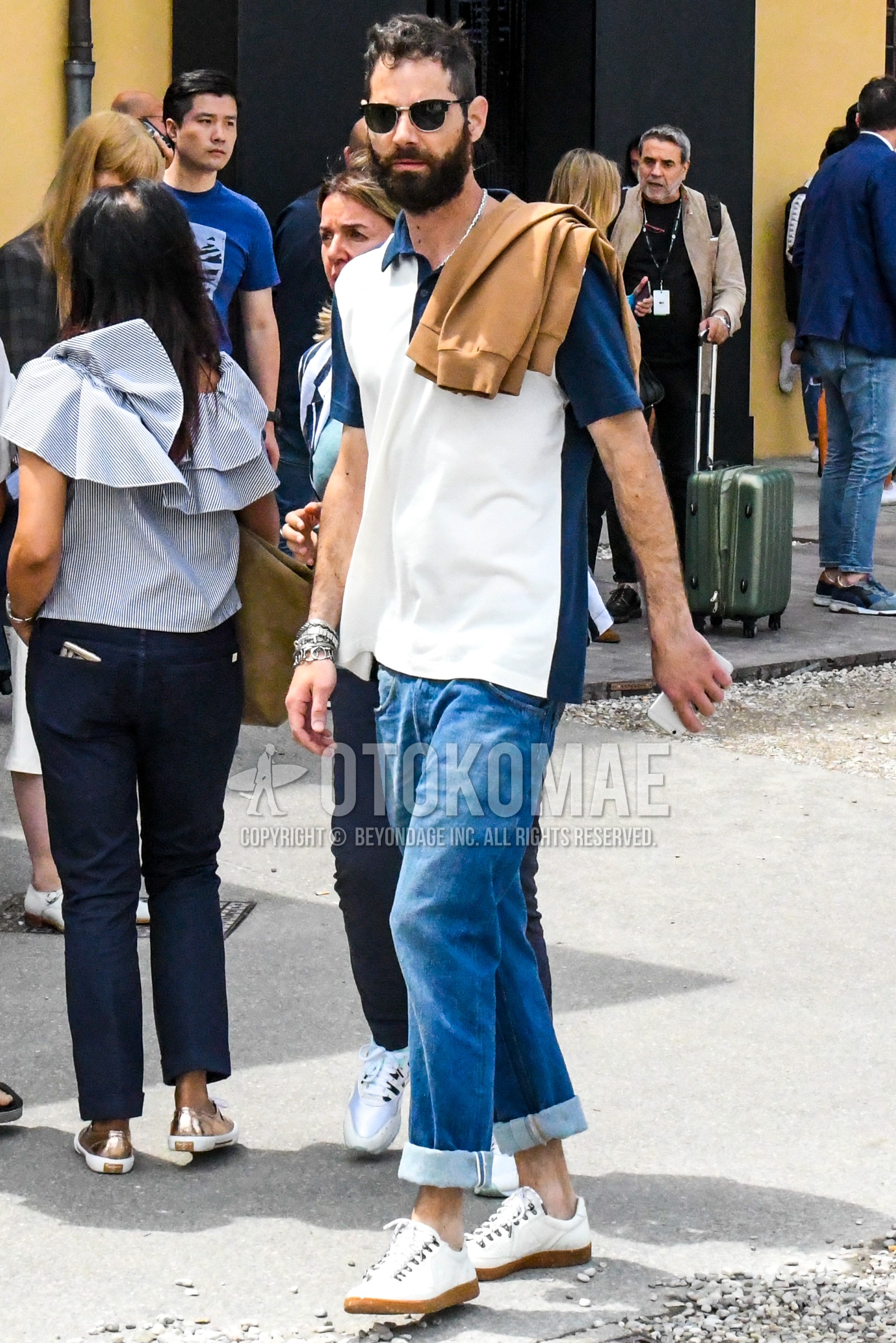 Men's summer outfit with plain sunglasses, white navy plain polo shirt, blue plain denim/jeans, white low-cut sneakers.