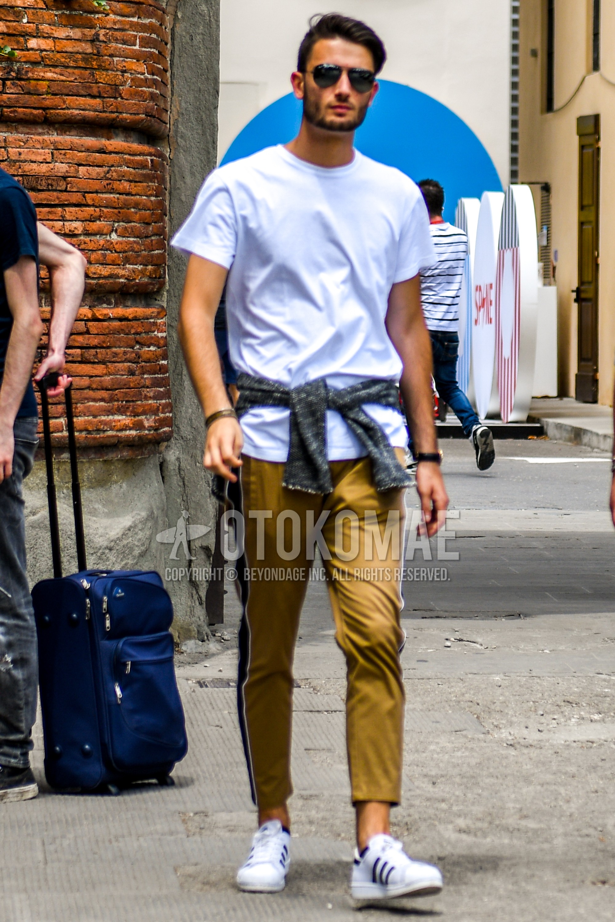 Men's summer outfit with plain sunglasses, white plain t-shirt, beige plain sideline pants, white low-cut sneakers.