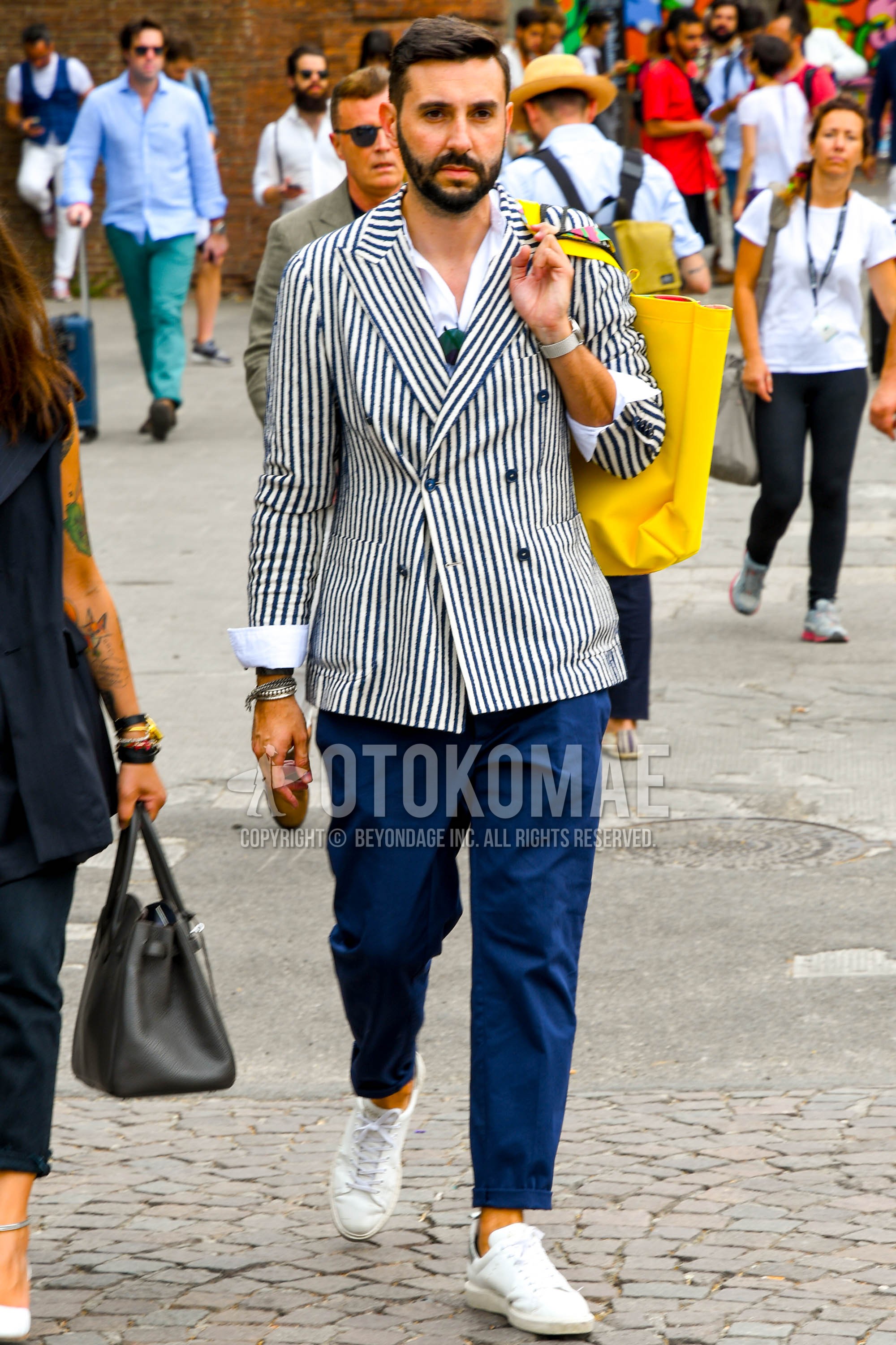 Men's spring summer autumn outfit with white black stripes tailored jacket, blue plain cotton pants, white low-cut sneakers.