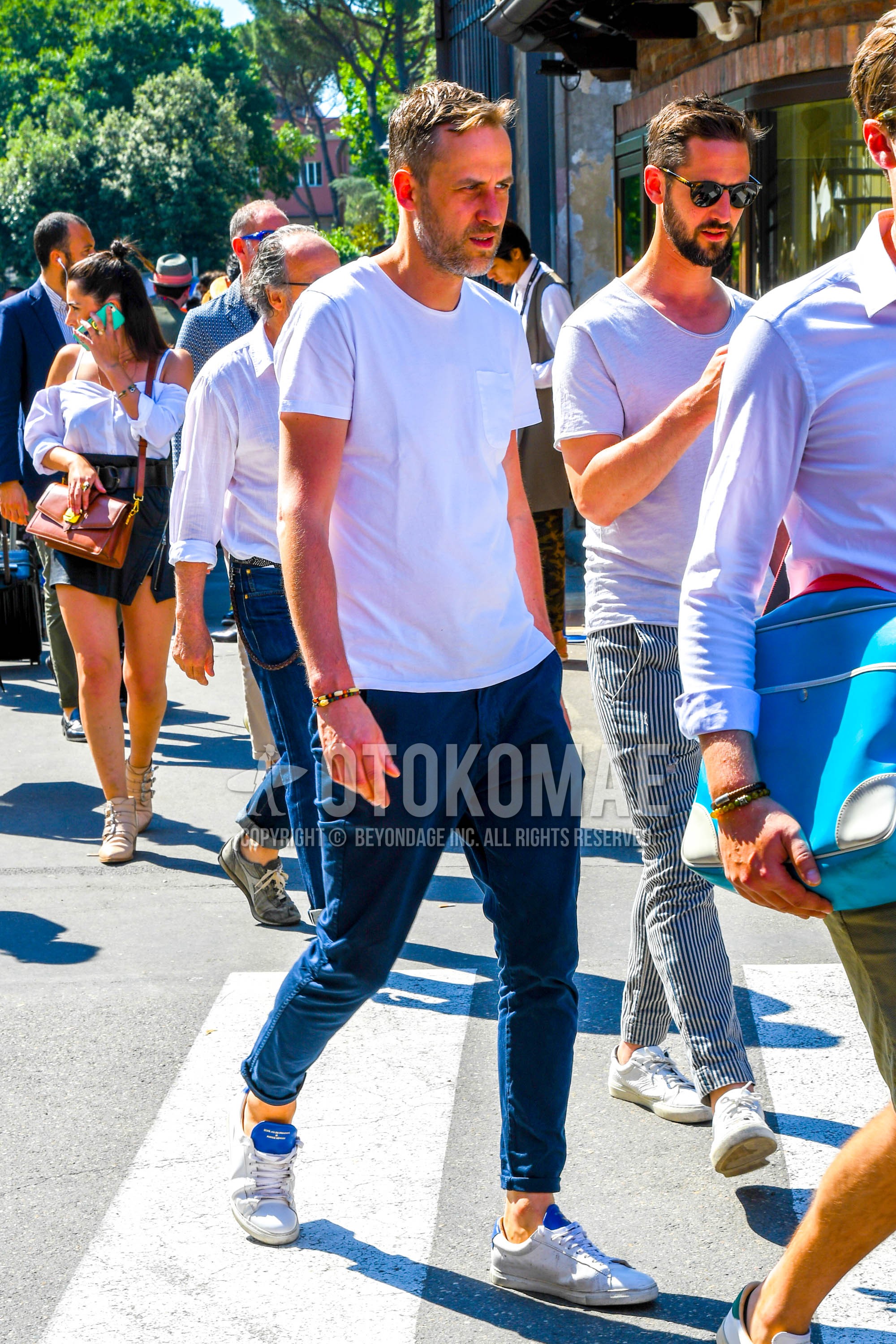 Men's summer outfit with white plain t-shirt, navy plain chinos, white low-cut sneakers.
