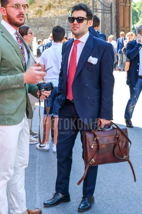 無地のサングラス、黒革靴、ブラウン無地のブリーフケース/ハンドバッグ、ネイビー無地のスーツ、レッドネクタイのネクタイを合わせた春夏秋のメンズコーデ・着こなし。