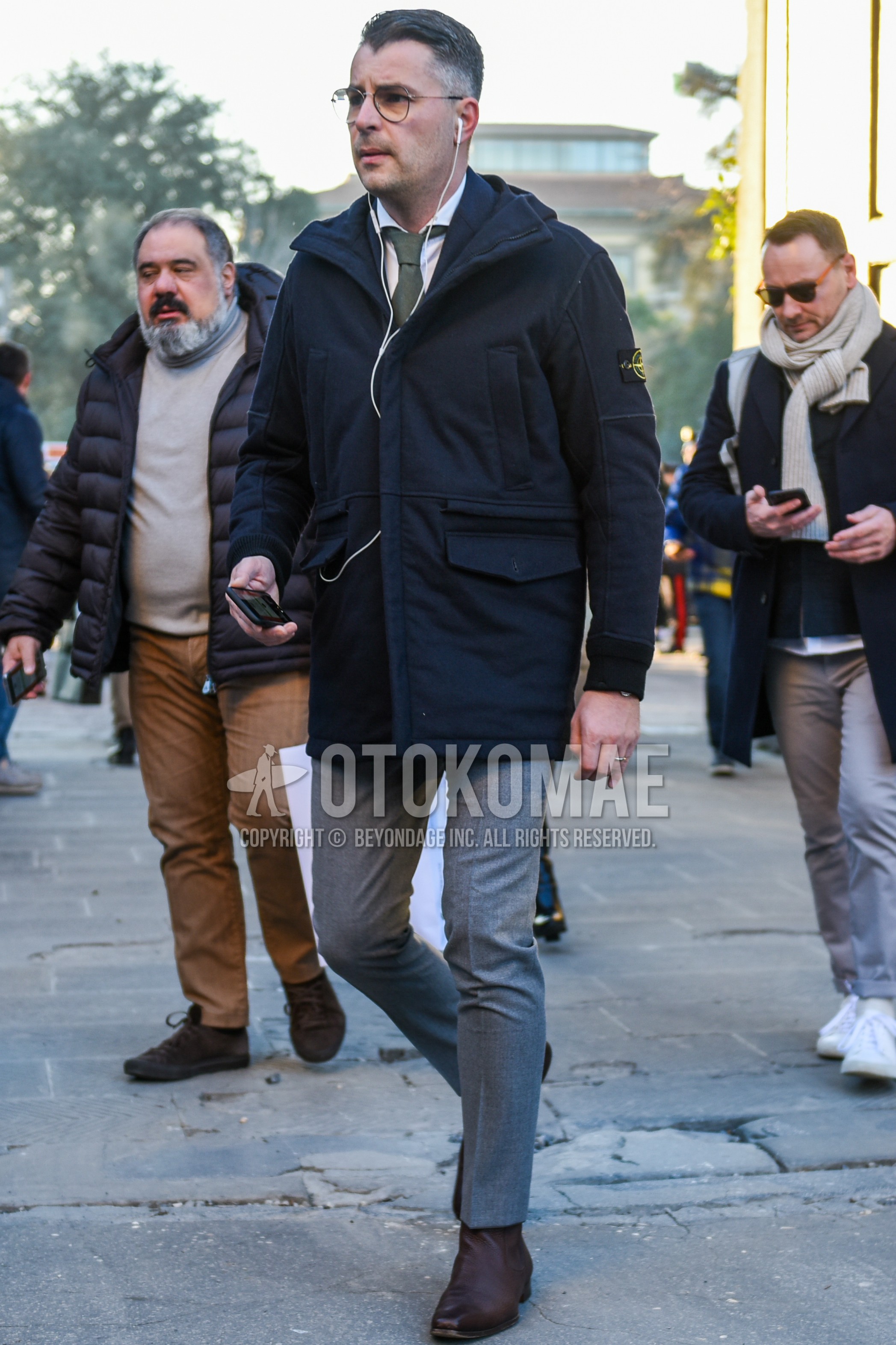 Men's autumn winter outfit with black plain glasses, black plain hooded coat, white plain shirt, gray plain slacks, gray plain cropped pants, brown side-gore boots, gray plain necktie.