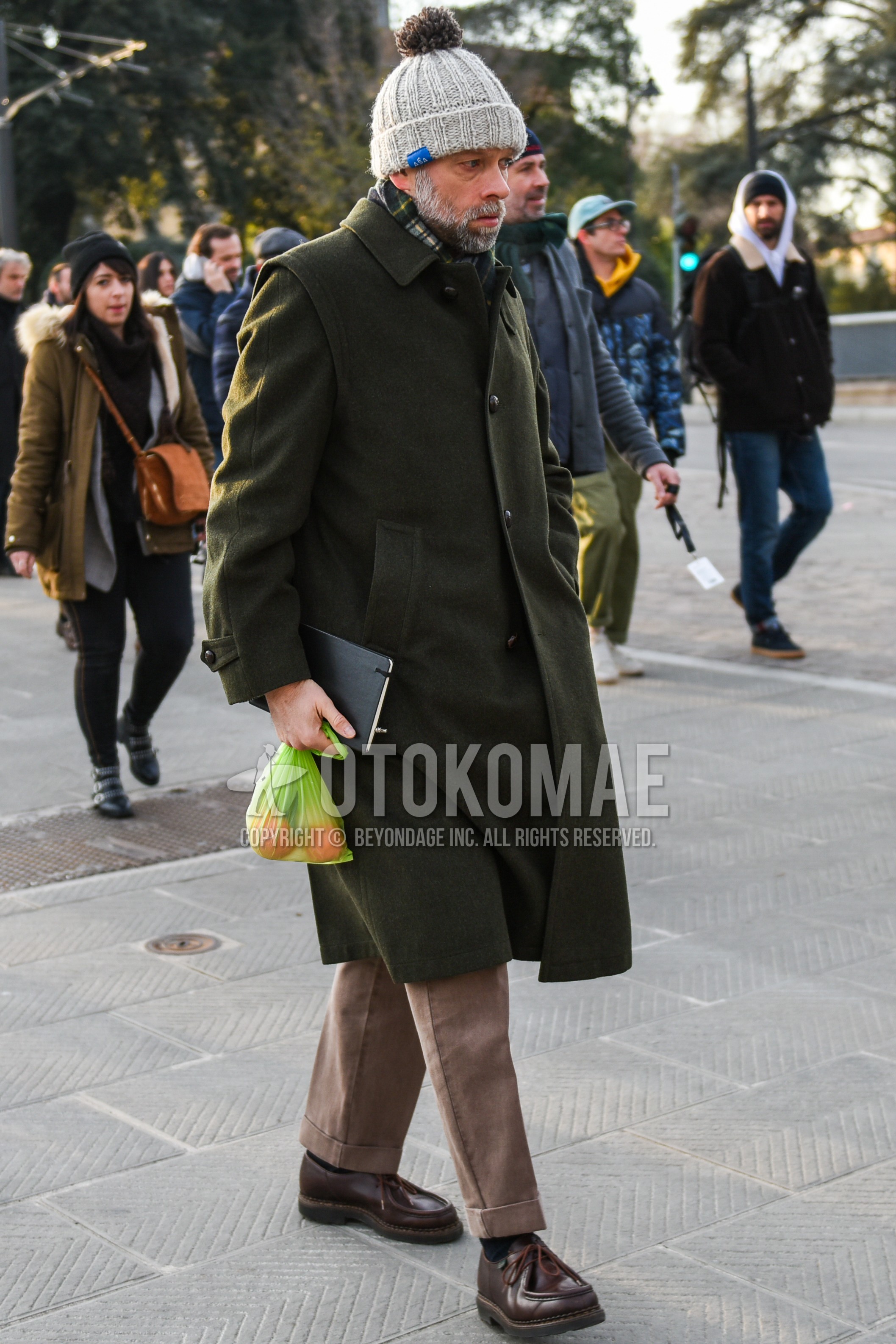 Men's autumn winter outfit with gray plain knit cap, green check scarf, olive green plain stenkarrer coat, beige plain slacks, beige plain ankle pants, black plain socks, brown  boots.