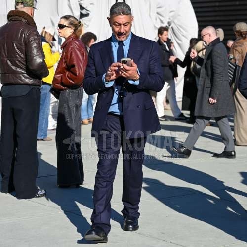 水色無地のデニム/シャンブレーシャツ、黒のブーツ、ネイビー無地のスーツ、ネイビー無地のニットタイを合わせた秋春のメンズコーデ・着こなし。