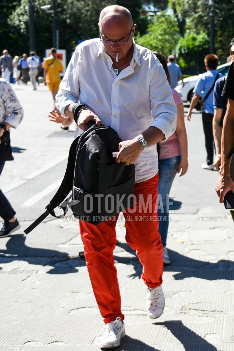 Men's spring summer outfit with plain glasses, white plain shirt, red plain cotton pants, white low-cut sneakers, black plain backpack.