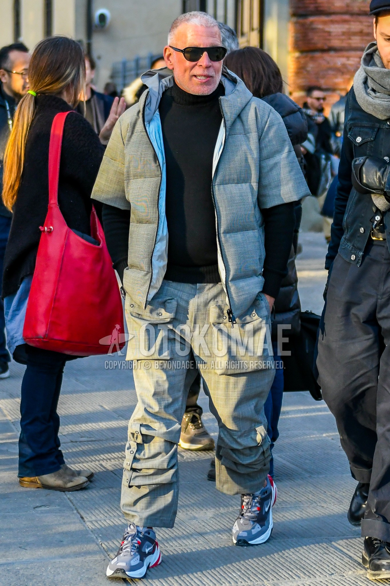 Men's winter outfit with plain sunglasses, gray plain down jacket, black plain turtleneck knit, gray plain cargo pants, gray low-cut sneakers.