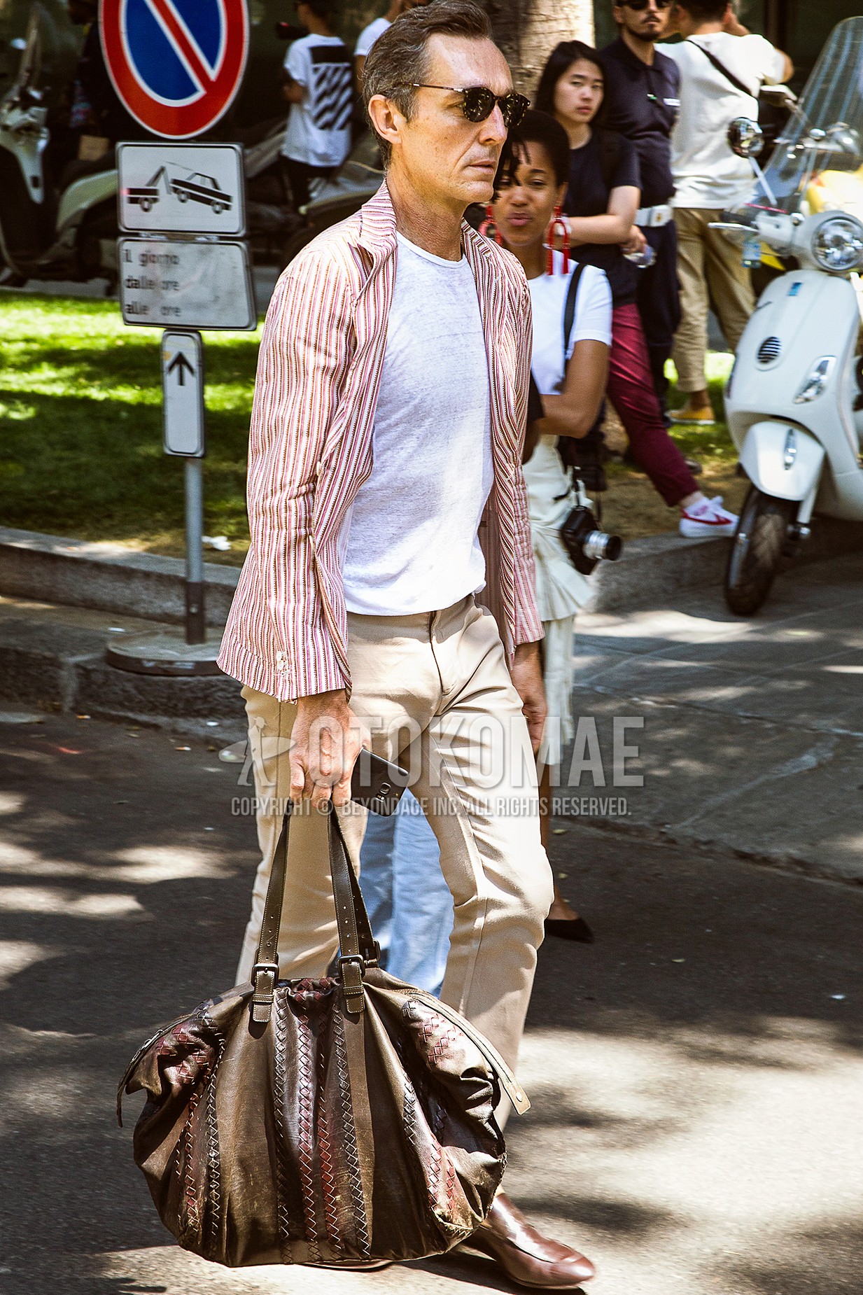 Men's spring summer autumn outfit with brown tortoiseshell sunglasses, pink stripes tailored jacket, white plain t-shirt, beige plain chinos, brown  loafers leather shoes, brown plain briefcase/handbag.