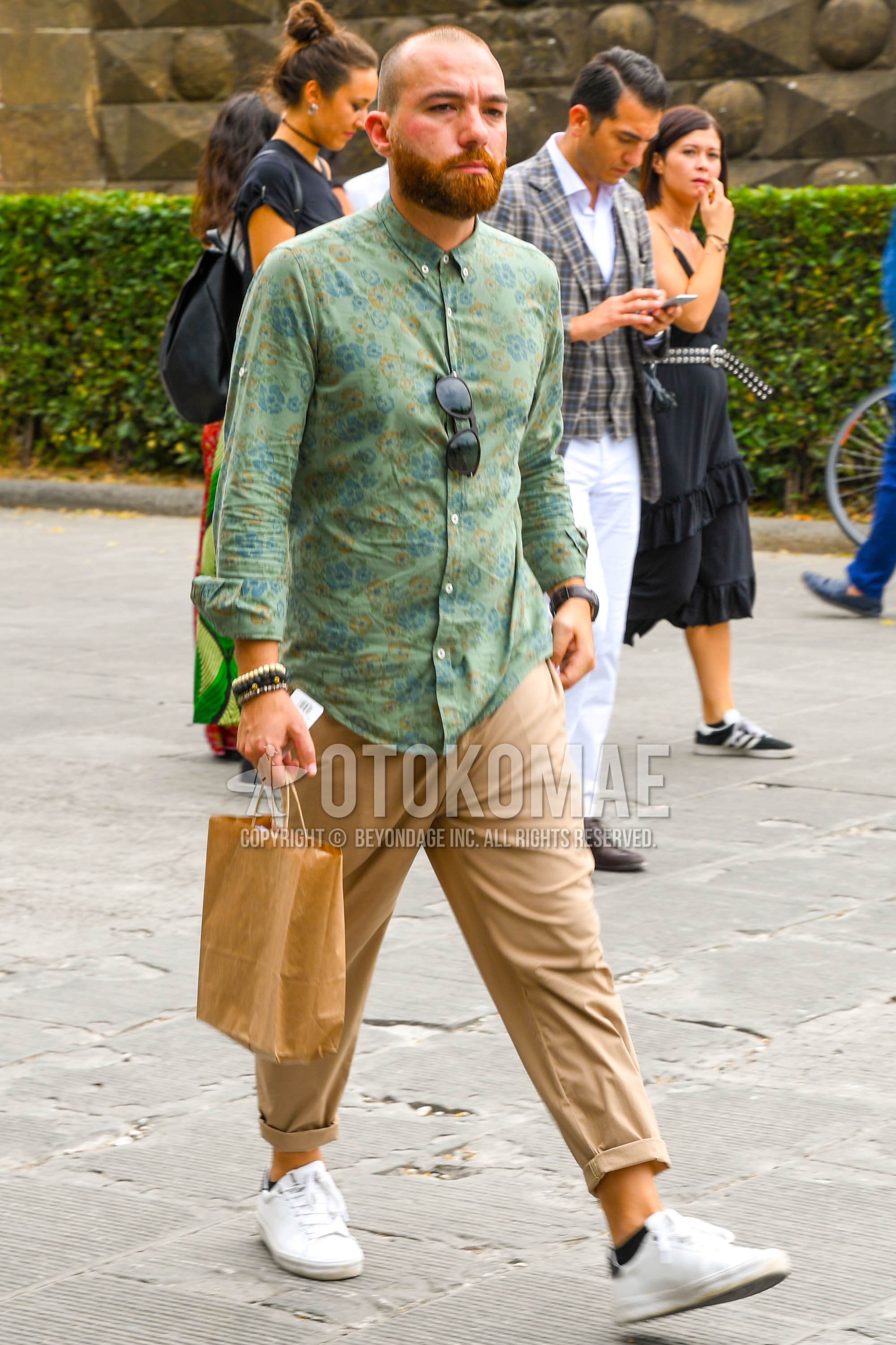 Men's spring summer outfit with green tops/innerwear shirt, beige plain chinos, white low-cut sneakers.