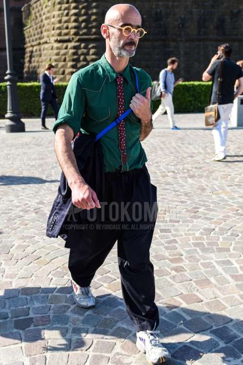 イエロー無地のメガネ、グリーン無地のシャツ、黒無地のスラックス、白ローカットのスニーカー、レッドネクタイのネクタイを合わせた春夏のメンズコーデ・着こなし。