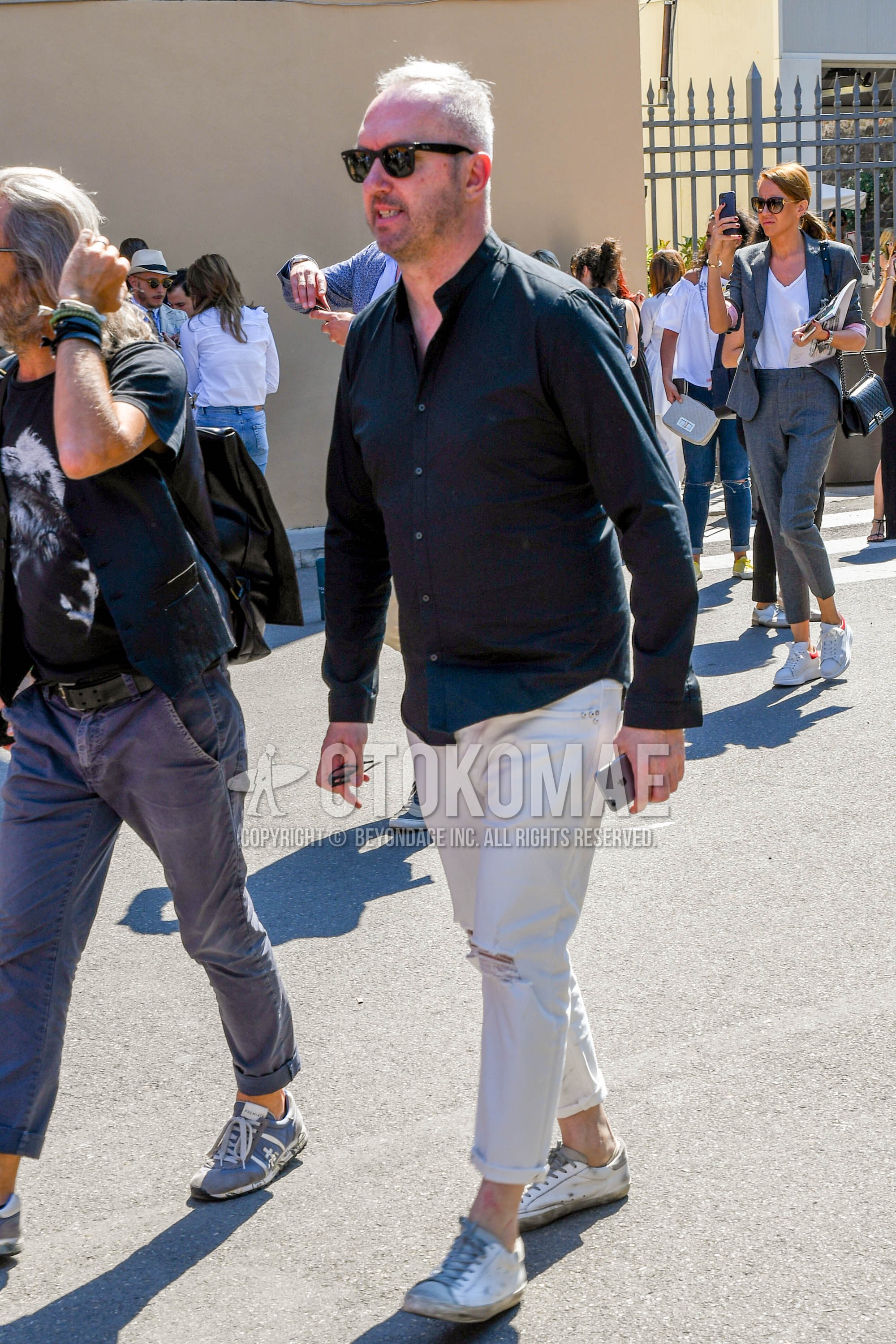 Men's spring summer autumn outfit with plain sunglasses, black plain shirt, white plain damaged jeans, white sneakers.