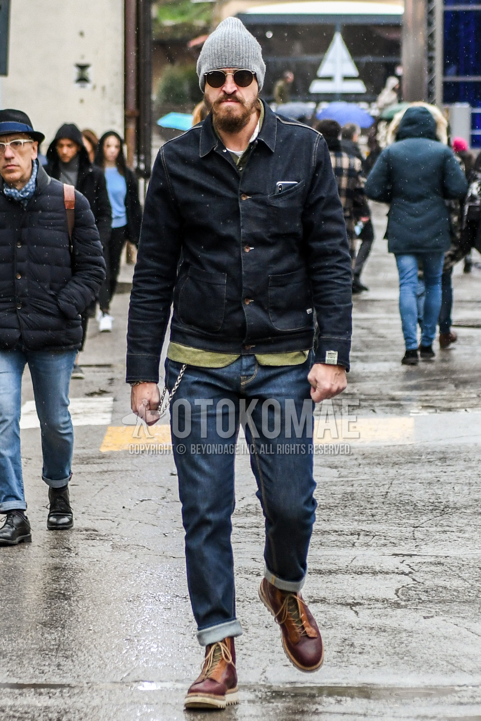 Men's autumn winter outfit with plain knit cap, black plain denim jacket, olive green plain shirt, blue plain denim/jeans, brown  boots.