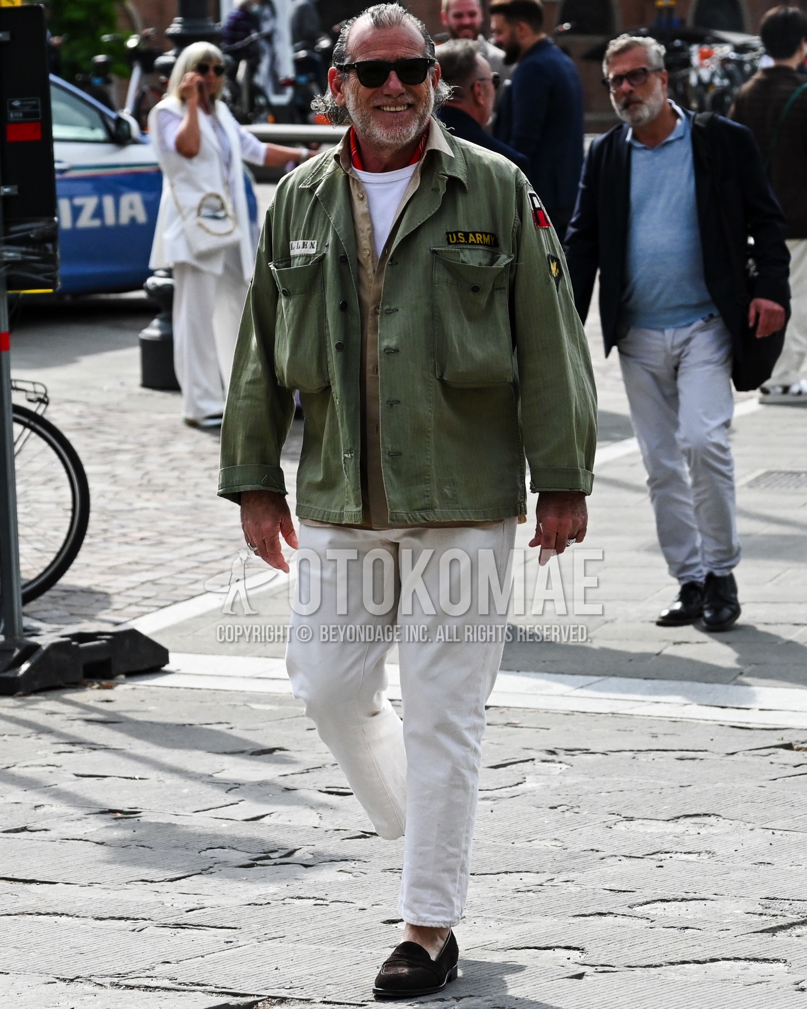 Men's spring summer autumn outfit with black plain sunglasses, red whole pattern bandana/neckerchief, olive green one point military jacket, beige plain shirt, white plain t-shirt, white plain chinos, brown coin loafers leather shoes.