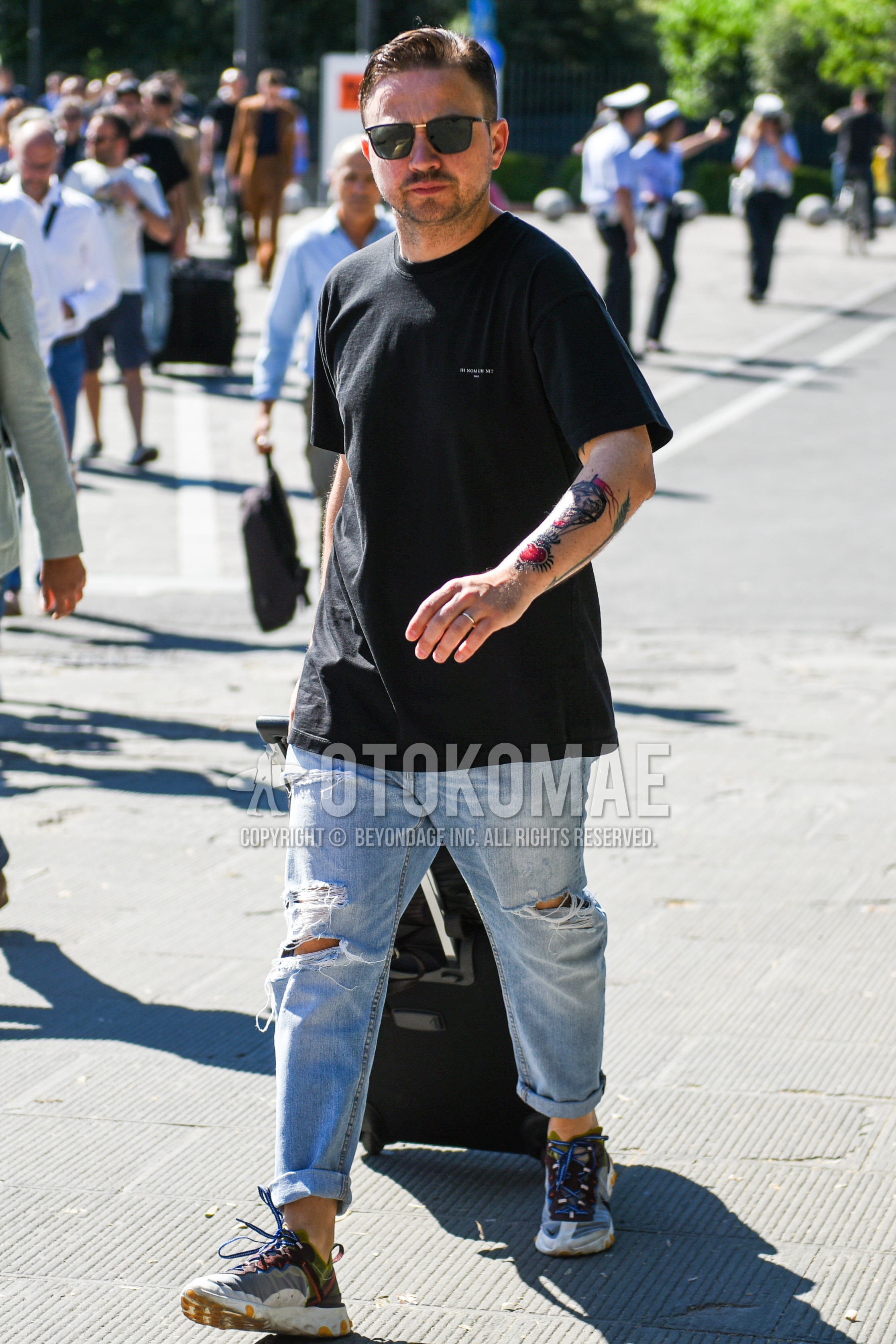 Men's summer outfit with black plain sunglasses, black one point t-shirt, light blue plain damaged jeans, clear low-cut sneakers.