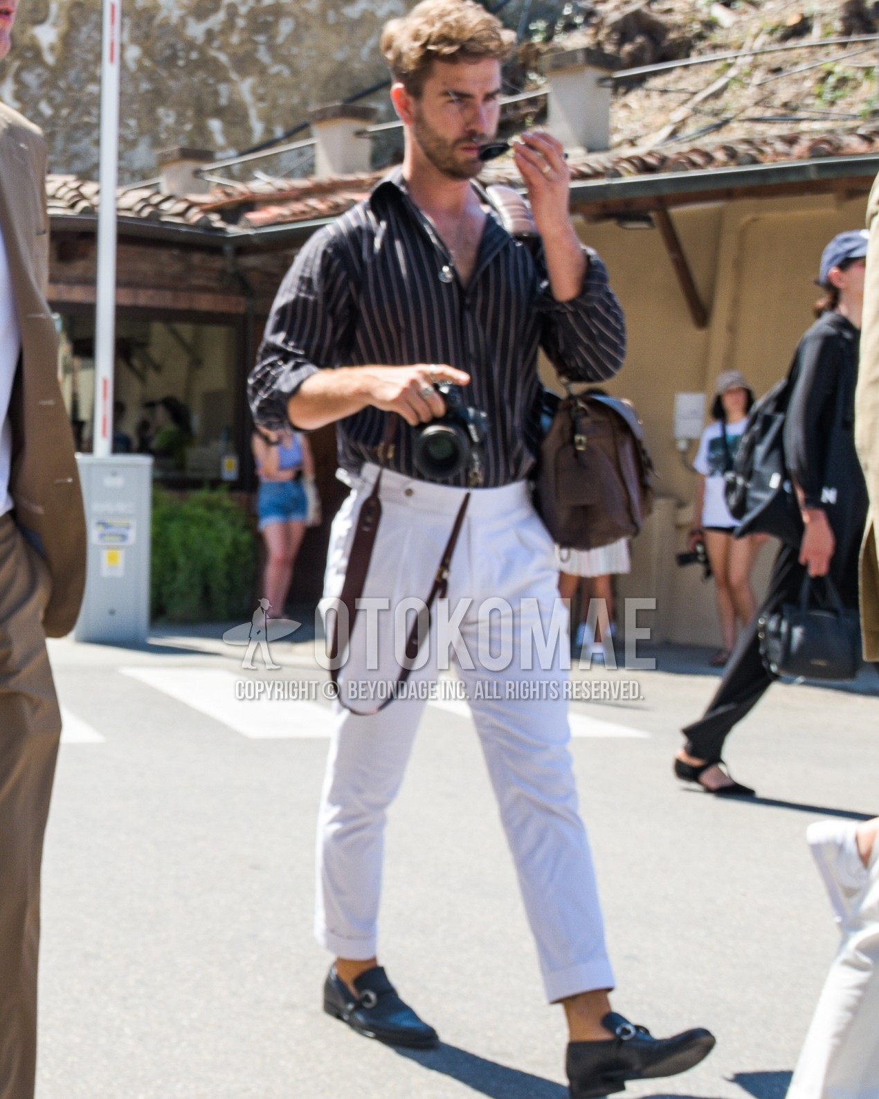 Men's spring summer outfit with dark gray stripes shirt, white plain beltless pants, white plain pleated pants, brown bit loafers leather shoes, brown plain shoulder bag.
