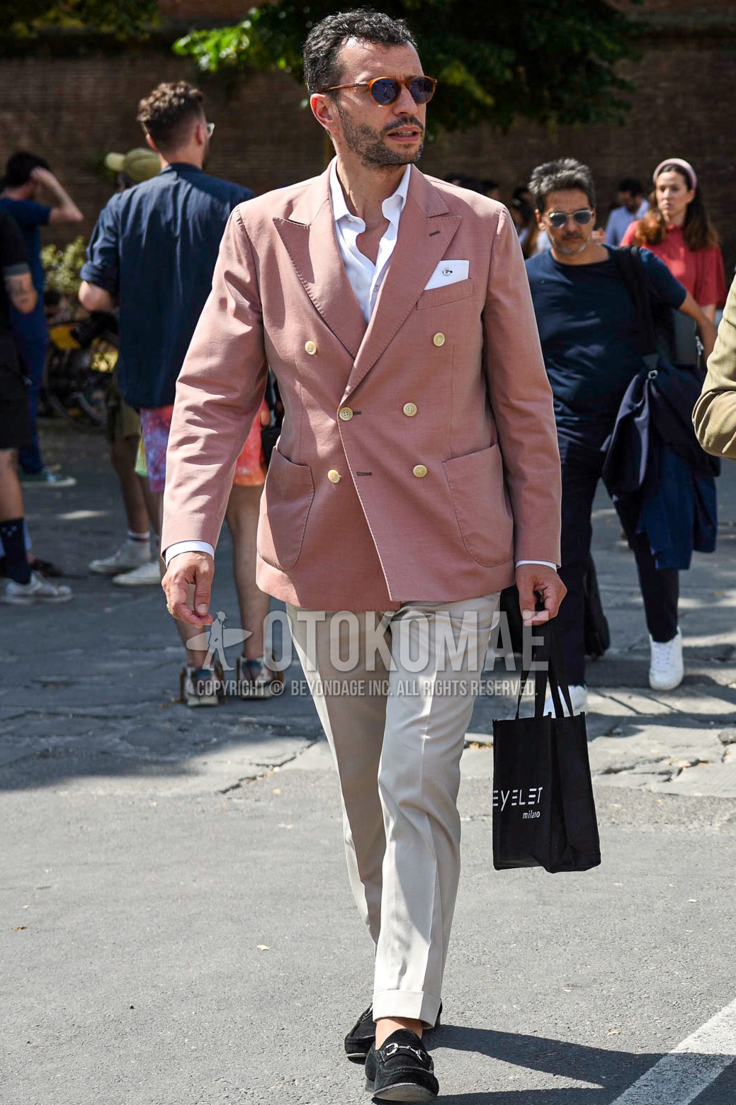 Men's spring summer autumn outfit with brown tortoiseshell sunglasses, pink plain tailored jacket, white plain shirt, beige plain cotton pants, black bit loafers leather shoes.