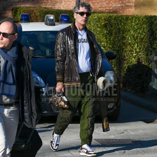 黒・レッド無地のサングラス、ブラウン・イエローアウターのスウィングトップ、白・黒無地のTシャツ、オリーブグリーン・グリーン無地のボトムス、白・ブラウンローカットのスニーカー、ブラウンバッグのクラッチバッグ/セカンドバッグ/巾着を合わせた秋春のメンズコーデ・着こなし。