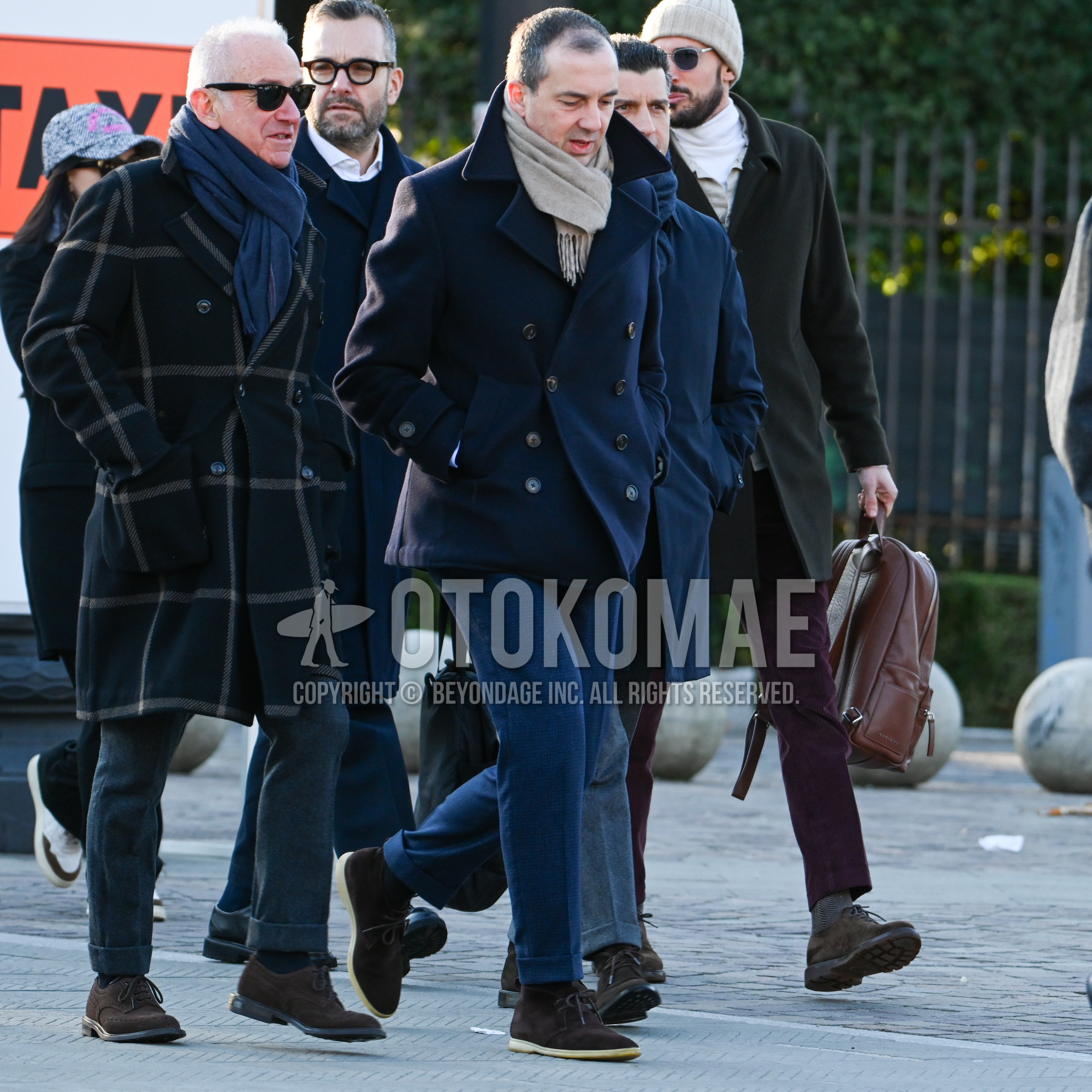 Men's autumn winter outfit with beige plain scarf, navy plain p coat, navy check slacks, brown chukka boots.