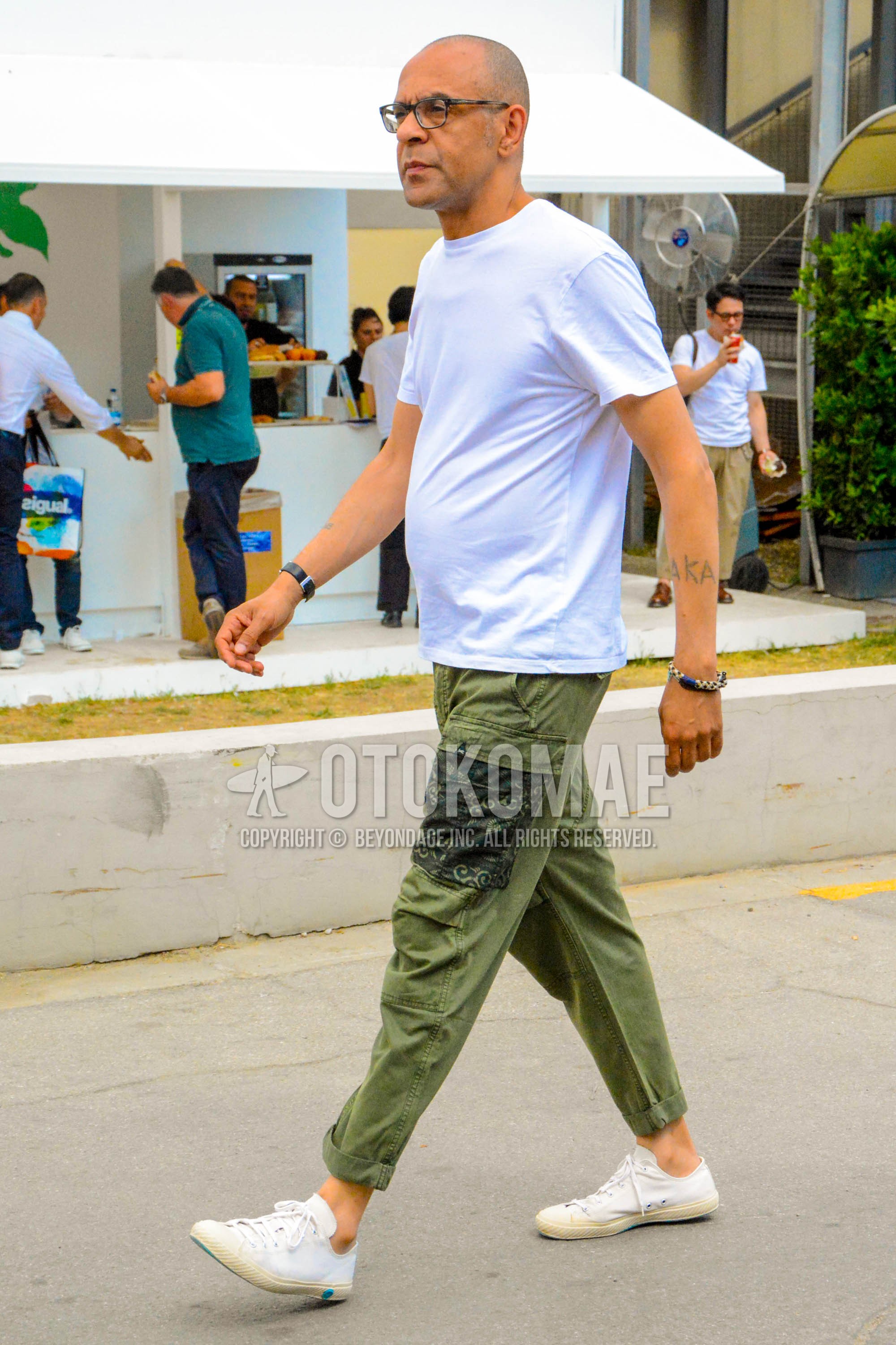 Men's summer outfit with plain glasses, white plain t-shirt, olive green plain cargo pants, white low-cut sneakers.