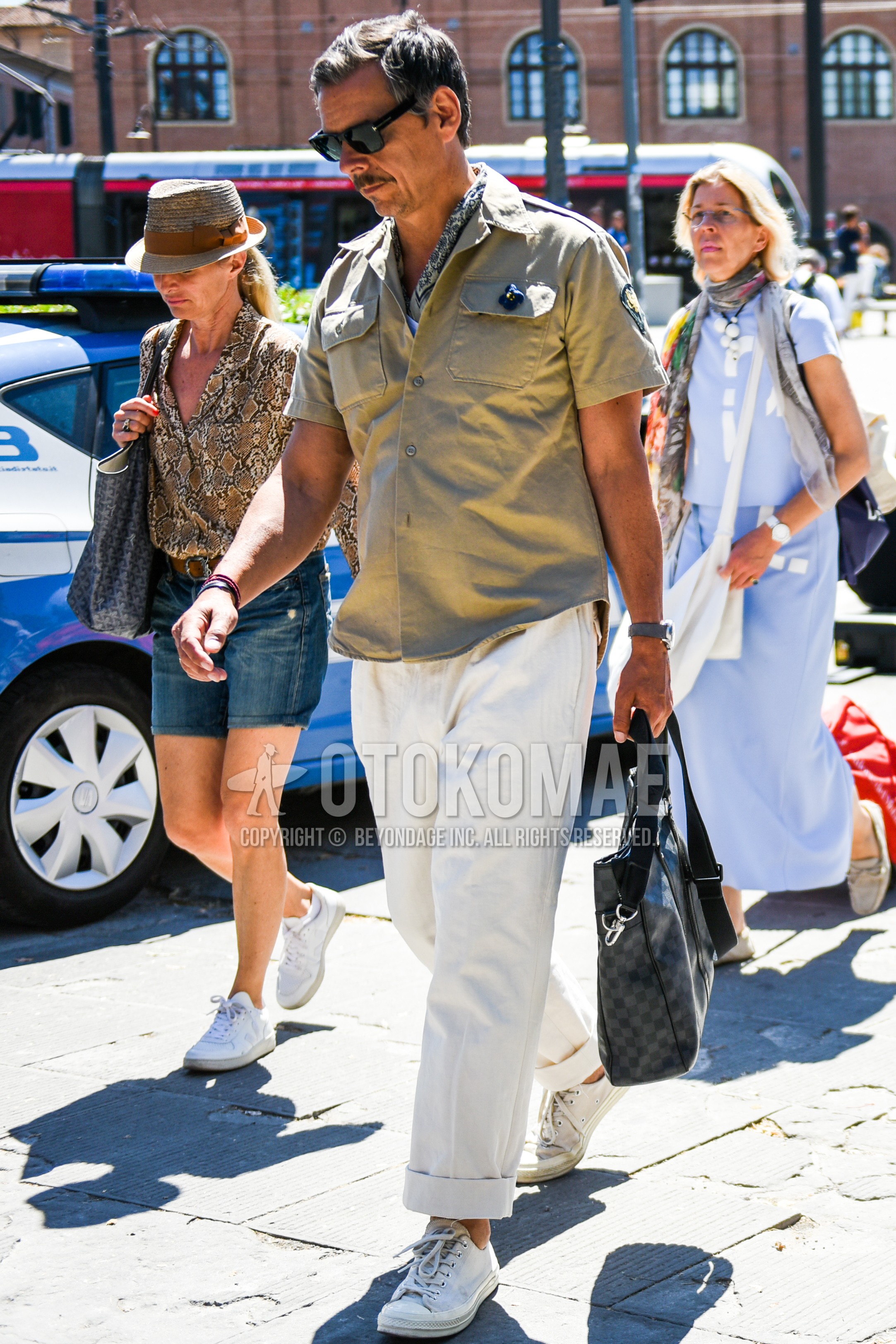 Men's summer outfit with black plain sunglasses, beige plain shirt jacket, white plain wide pants, white low-cut sneakers, dark gray check briefcase/handbag.