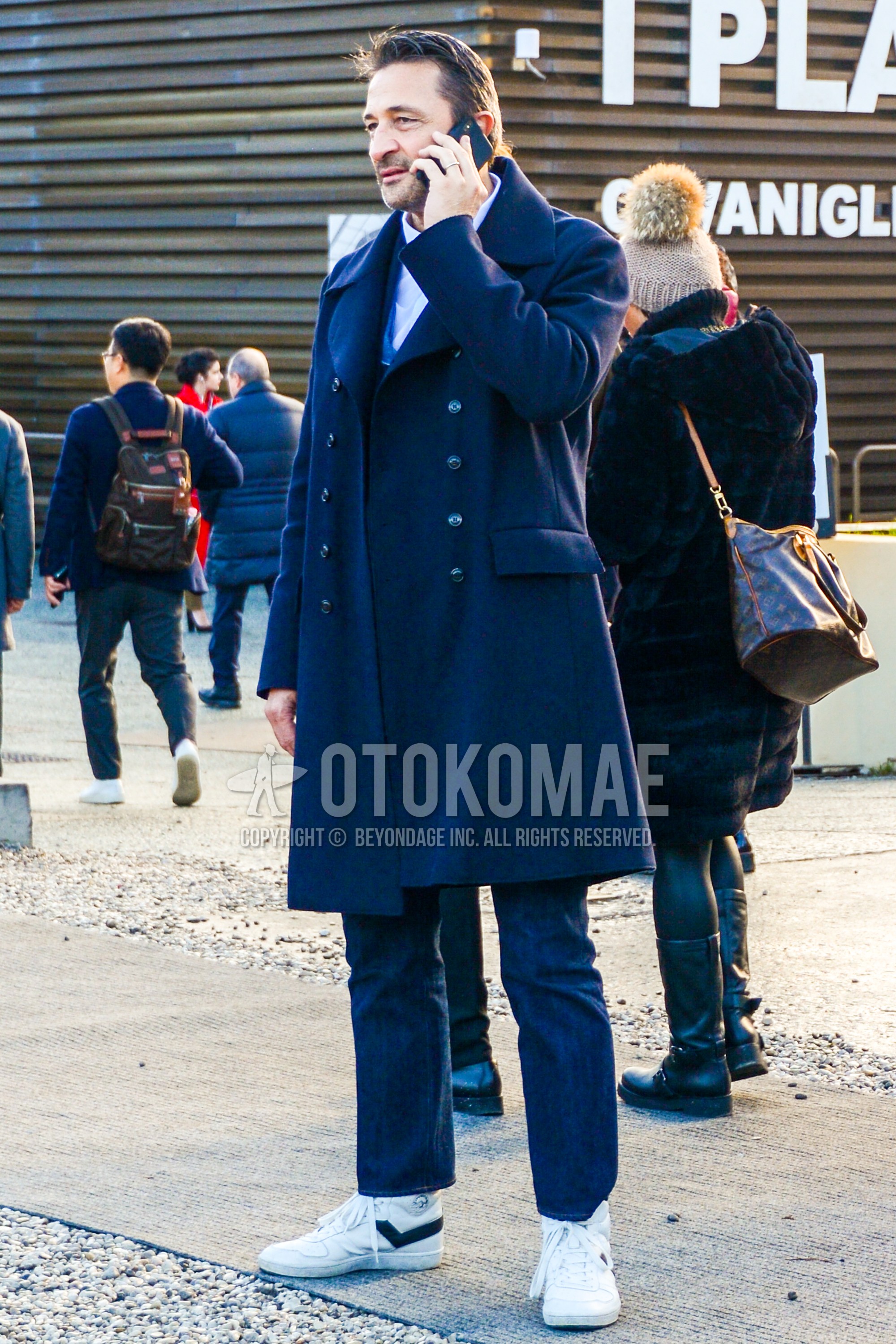 Men's winter outfit with navy plain ulster coat, white plain shirt, navy plain denim/jeans, white high-cut sneakers.