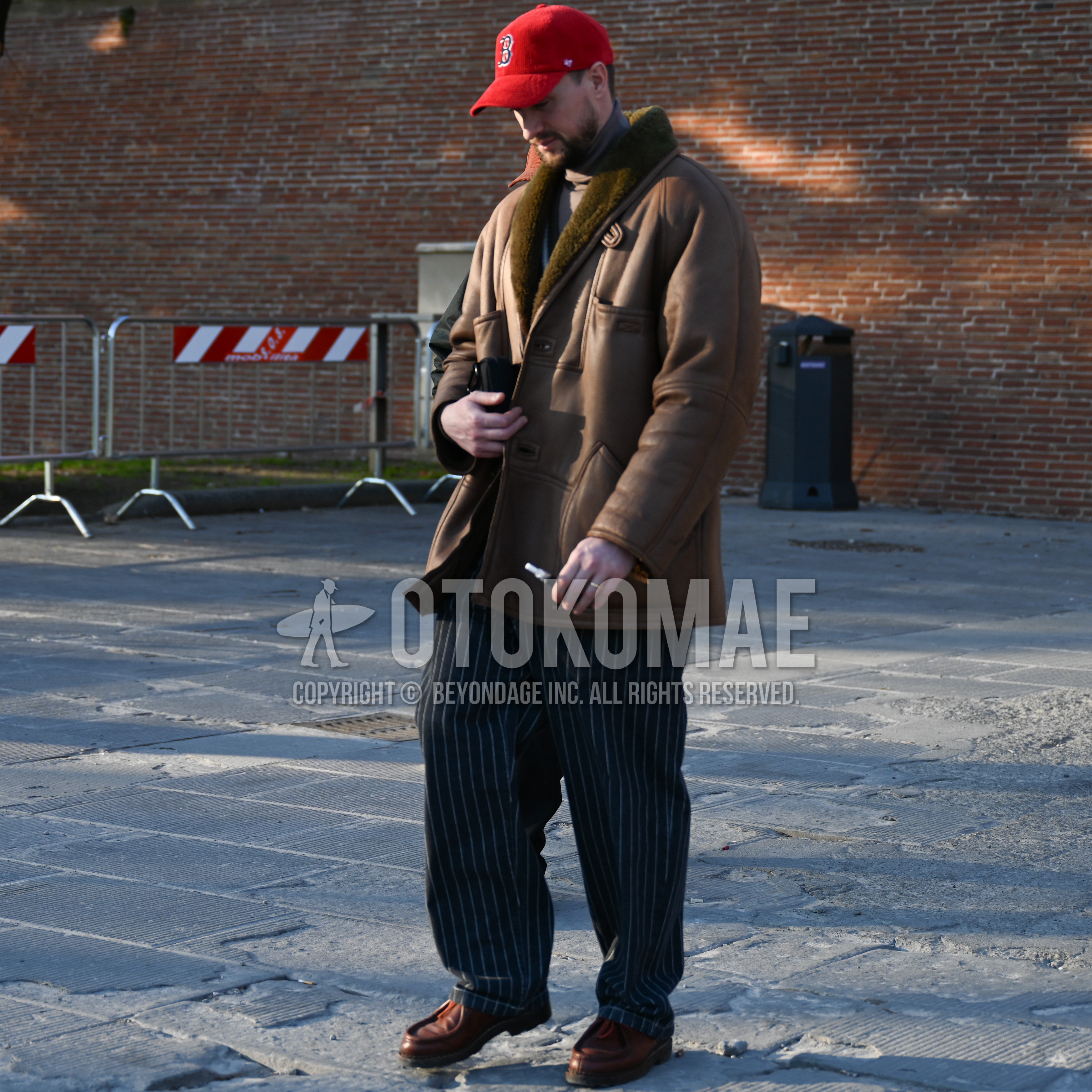 Men's autumn winter outfit with red one point baseball cap, brown outerwear, beige plain turtleneck knit, navy stripes slacks, brown  loafers leather shoes.