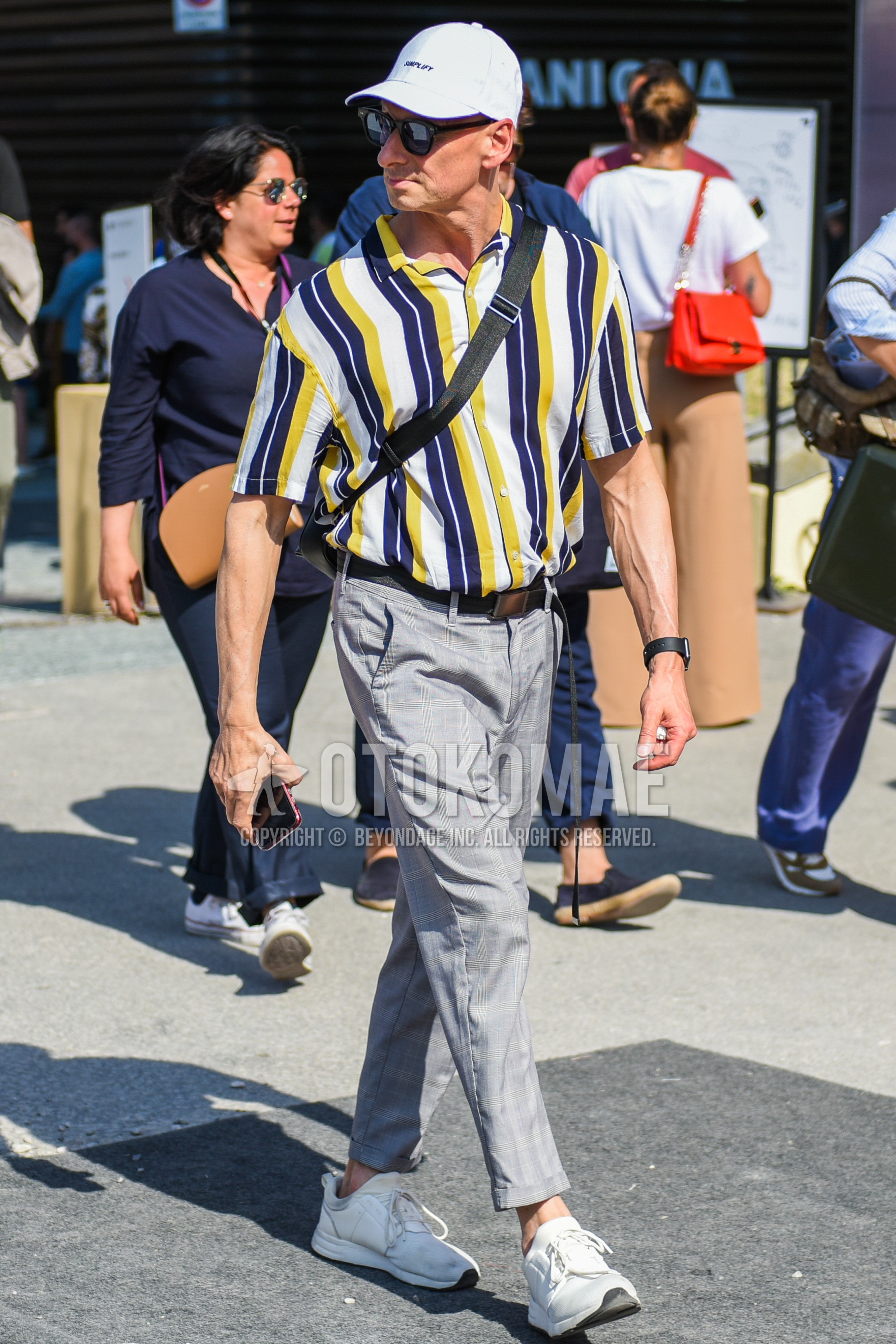 Men's spring summer outfit with white one point baseball cap, black plain sunglasses, yellow white navy stripes shirt, black plain leather belt, gray check slacks, gray check ankle pants, white low-cut sneakers.