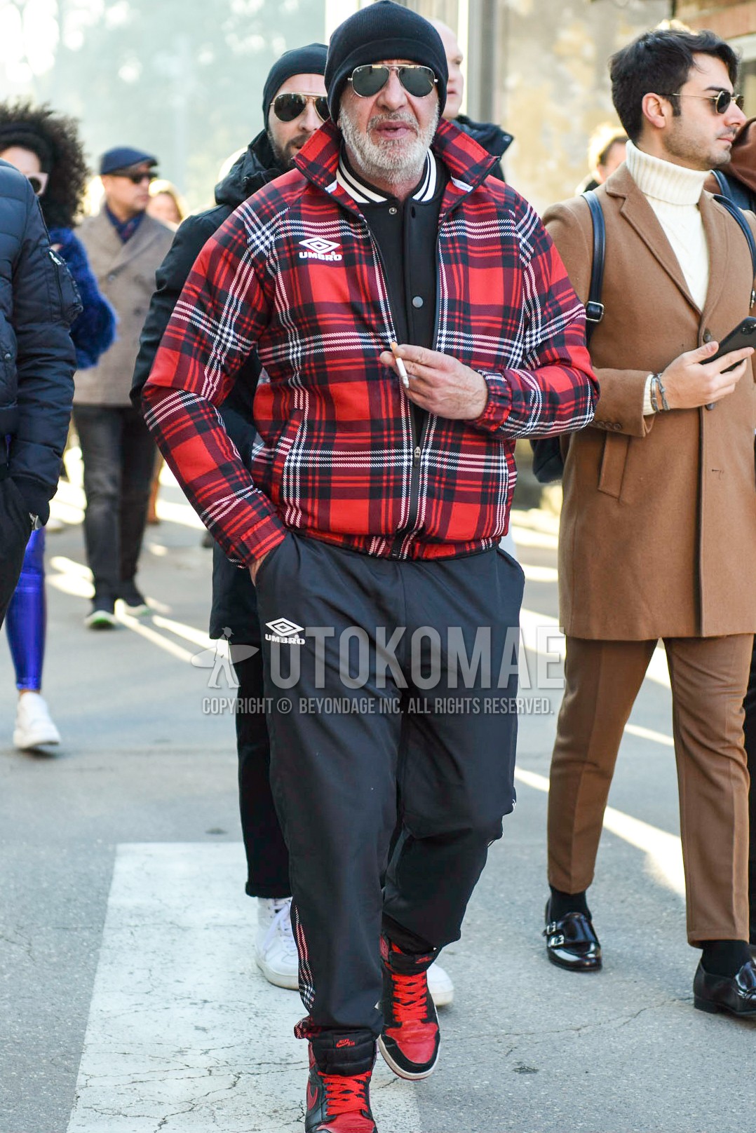 Men's autumn winter outfit with black plain knit cap, gold plain sunglasses, red check windbreaker, black plain stadium jacket, gray plain sideline pants, red black high-cut sneakers.