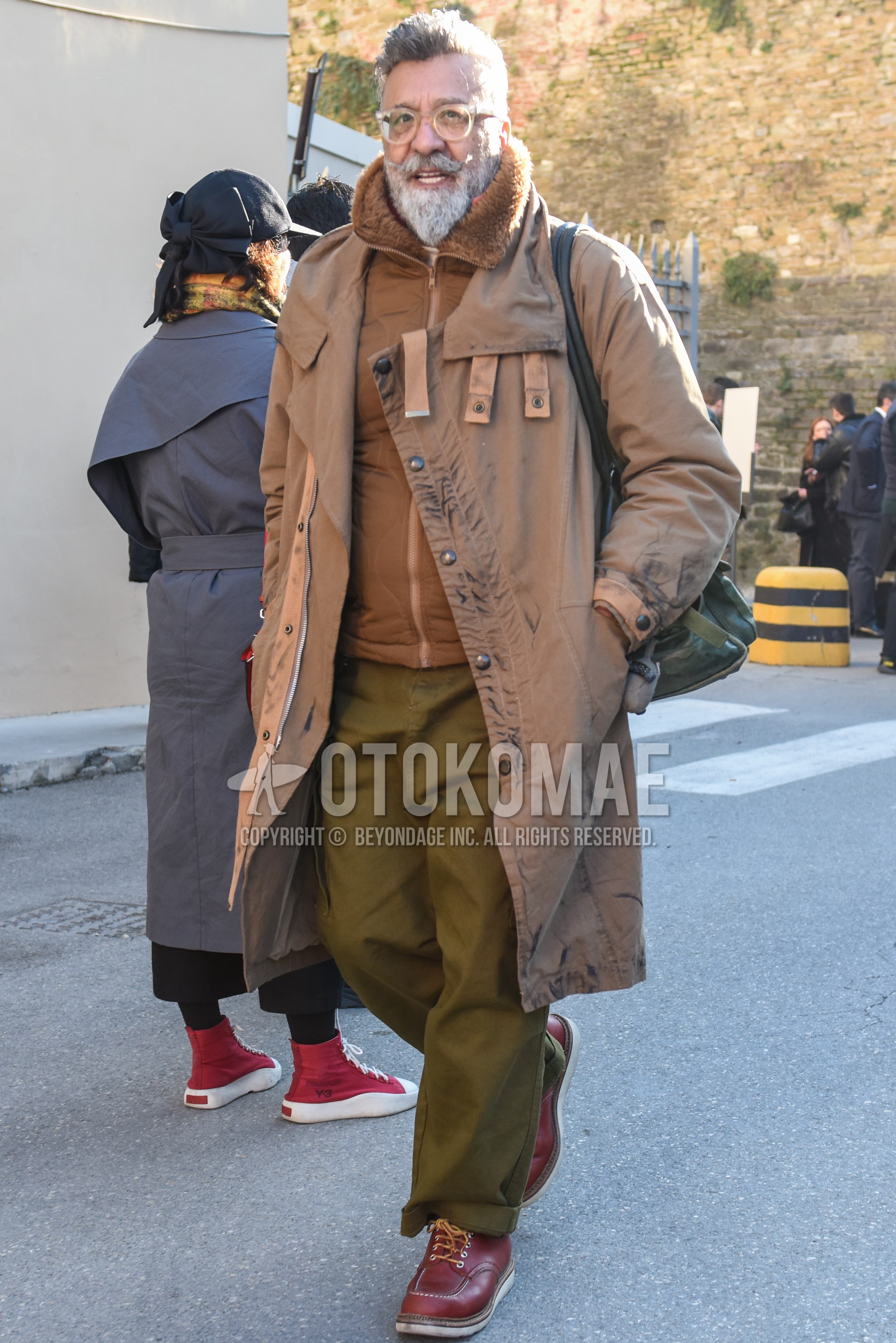 Men's autumn winter outfit with clear beige plain glasses, beige plain hooded coat, brown plain outerwear, olive green plain cargo pants, olive green plain chinos, brown work boots.