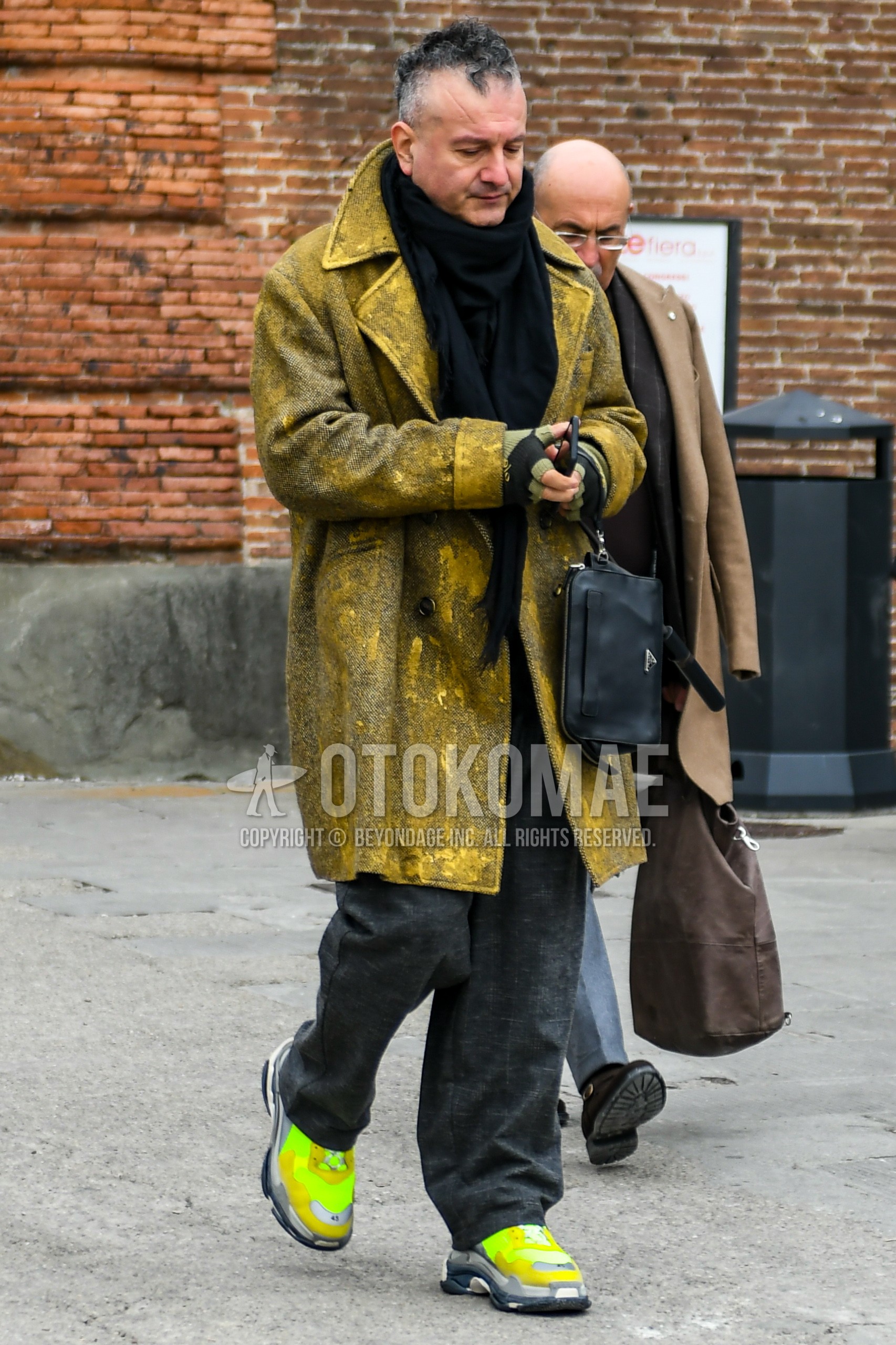 Men's winter outfit with black plain scarf, yellow outerwear ulster coat, gray check slacks, yellow low-cut sneakers.