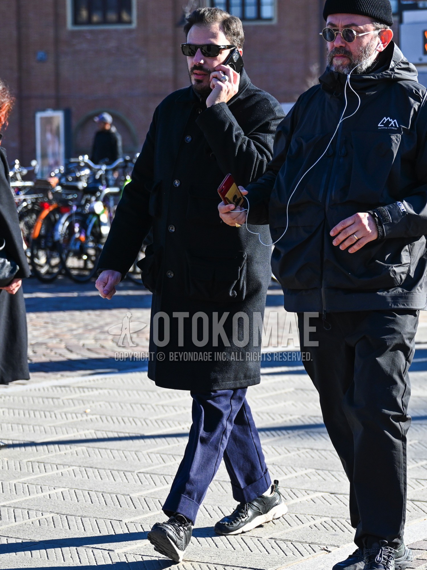 Men's autumn winter outfit with black plain sunglasses, black plain stenkarrer coat, navy plain slacks, white plain socks, black low-cut sneakers.