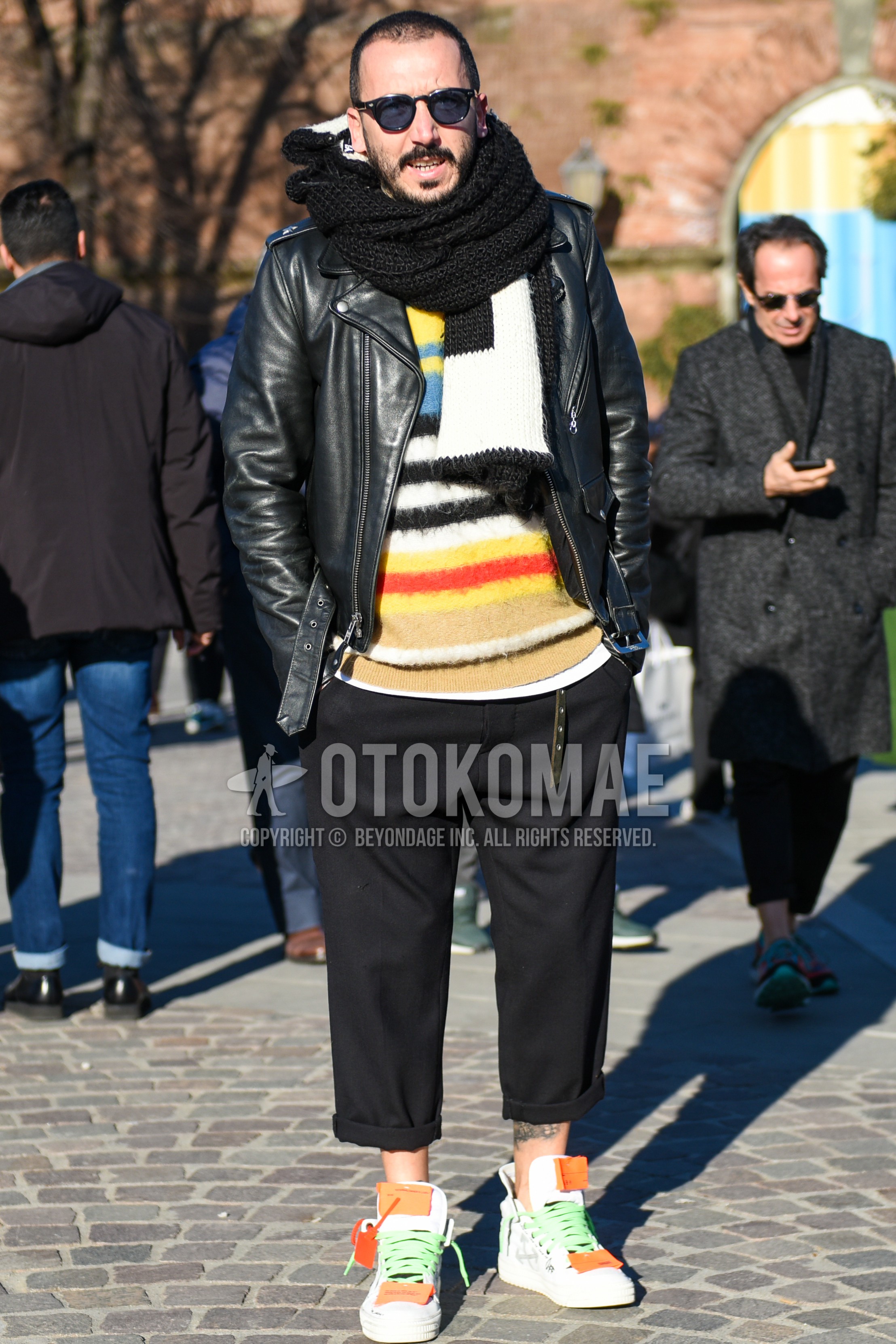 Men's autumn winter outfit with black plain sunglasses, black plain scarf, black plain riders jacket, multi-color tops/innerwear sweater, black plain slacks, white high-cut sneakers.