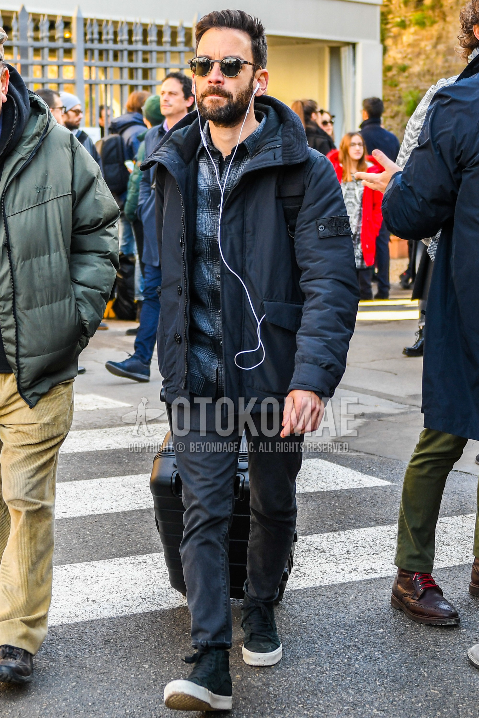 Men's winter outfit with black plain down jacket, dark gray check shirt, dark gray plain chinos, black high-cut sneakers.