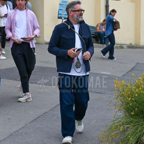 黒無地のメガネ、ブルー無地のシャツジャケット、白無地のTシャツ、ブルー無地のスラックス、白・オリーブグリーンローカットのスニーカーを合わせた春秋のメンズコーデ・着こなし。