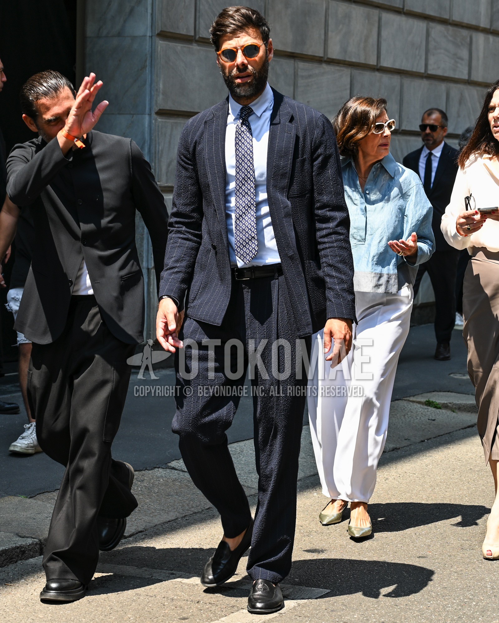 Men's spring summer autumn outfit with black plain sunglasses, white plain shirt, black coin loafers leather shoes, navy stripes suit, navy small crest necktie.