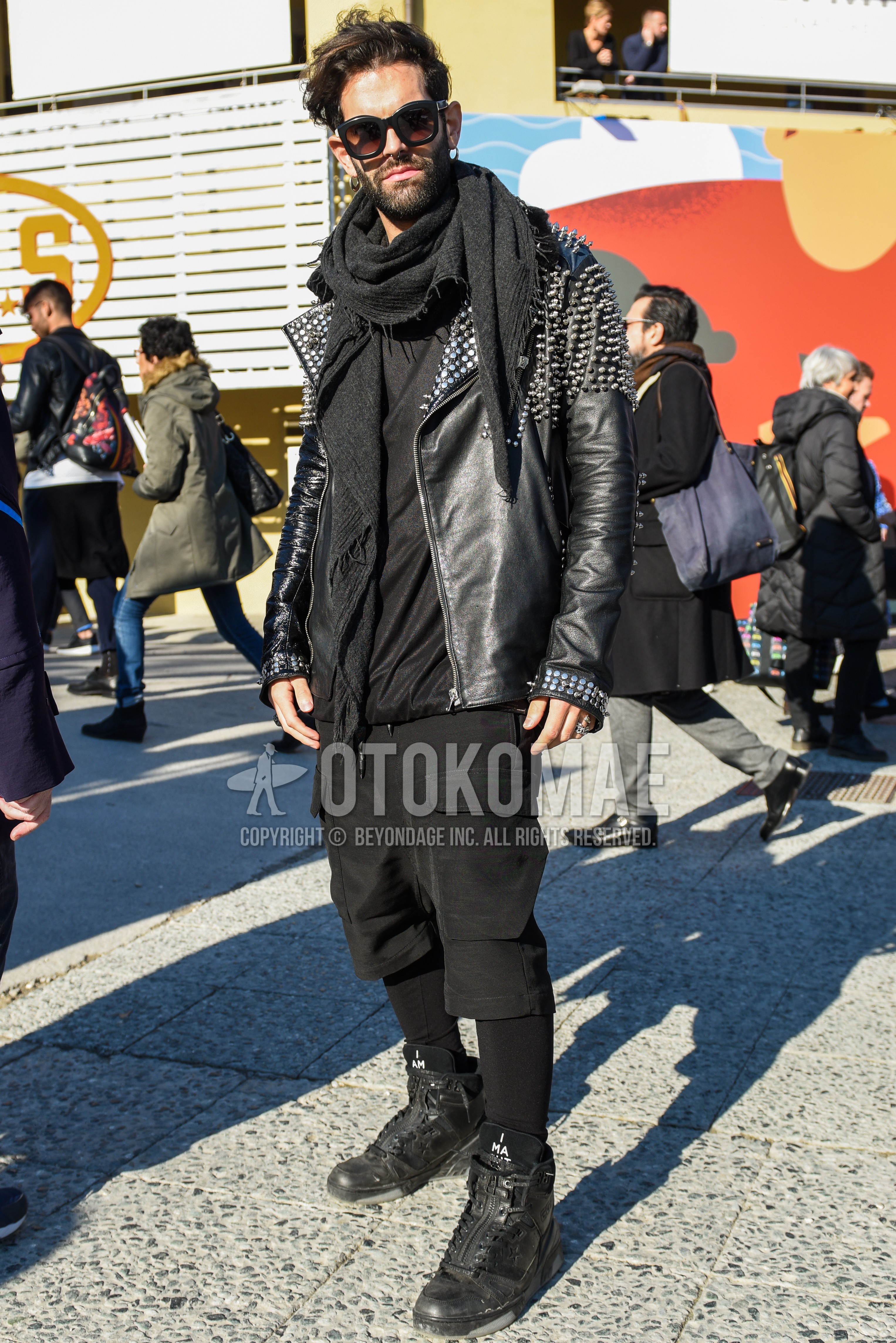 Men's spring autumn outfit with black plain sunglasses, dark gray plain scarf, black plain riders jacket, black plain short pants, black plain cargo pants, black high-cut sneakers.