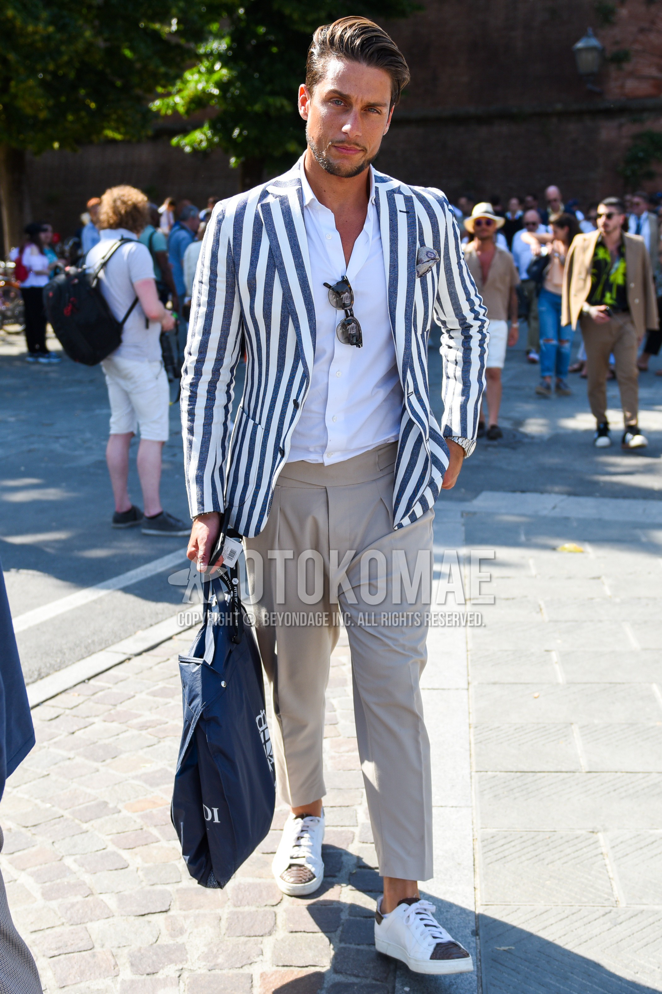 Men's spring autumn outfit with white gray stripes tailored jacket, white plain shirt, beige plain beltless pants, white low-cut sneakers.