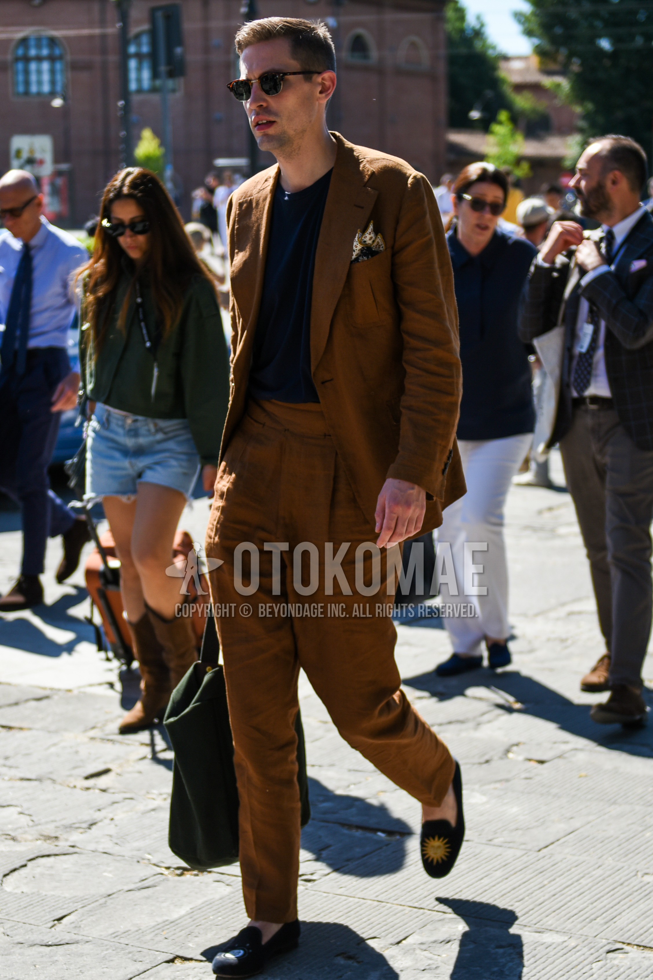 Men's spring summer autumn outfit with brown tortoiseshell sunglasses, navy plain t-shirt, navy  loafers leather shoes, olive green plain briefcase/handbag, brown plain suit.