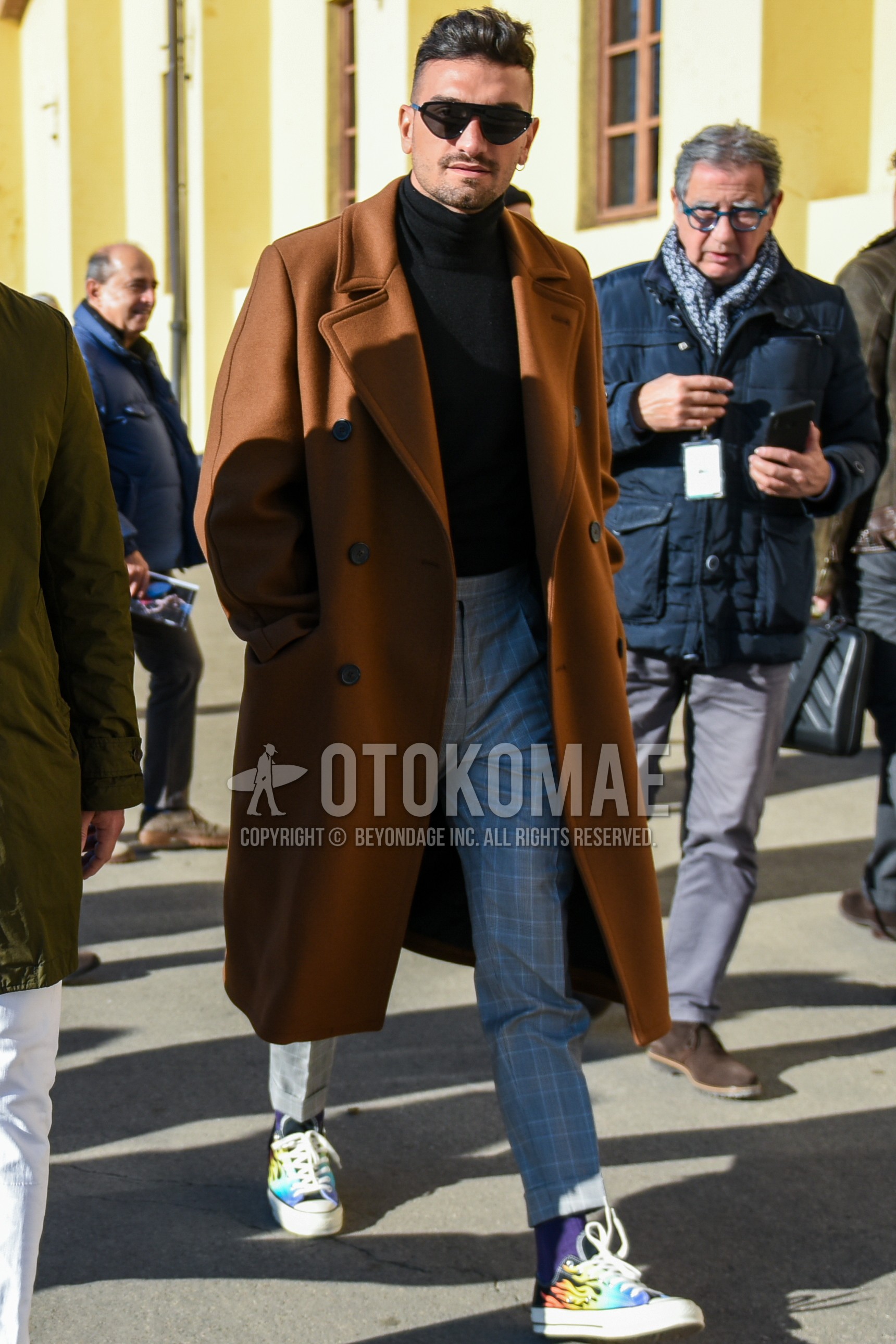 Men's autumn winter outfit with black plain sunglasses, brown plain chester coat, black plain turtleneck knit, gray check slacks, gray check cropped pants, purple plain socks, multi-color low-cut sneakers.