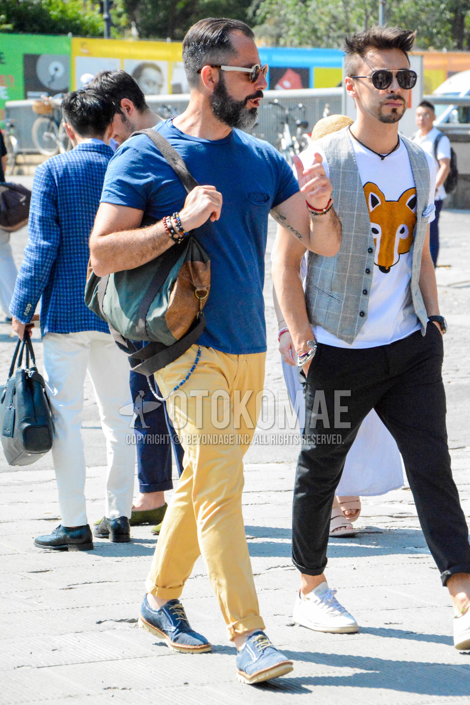 Men's spring summer outfit with white plain sunglasses, blue plain t-shirt, yellow plain cotton pants, navy plain toe leather shoes, gray plain shoulder bag.