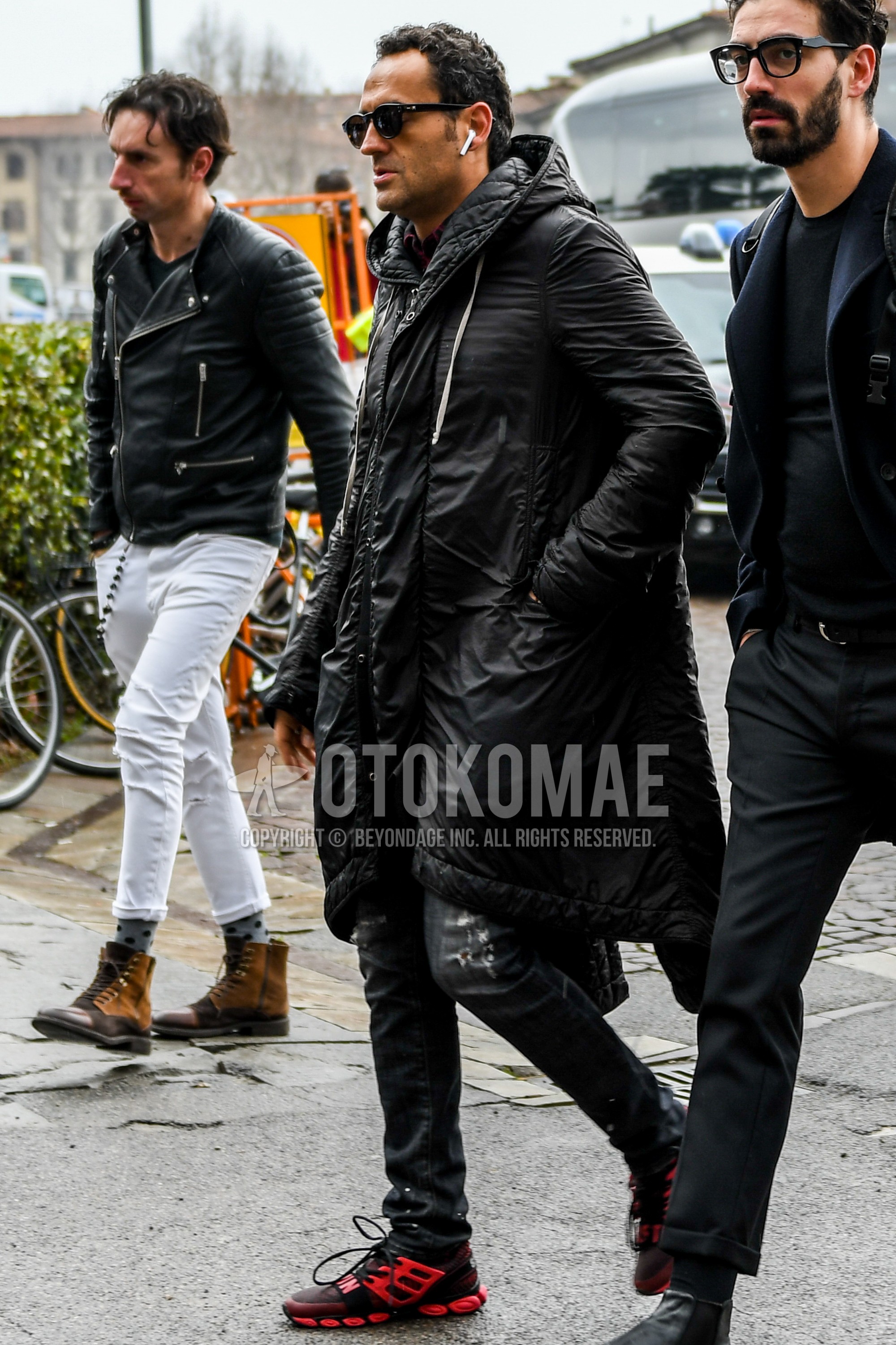 Men's winter outfit with plain sunglasses, black plain hooded coat, black plain damaged jeans, red low-cut sneakers.