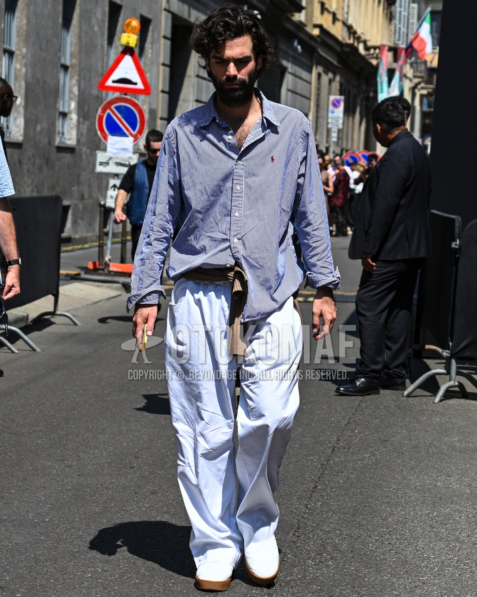 Men's spring summer autumn outfit with blue plain shirt, light blue plain wide pants, white low-cut sneakers.